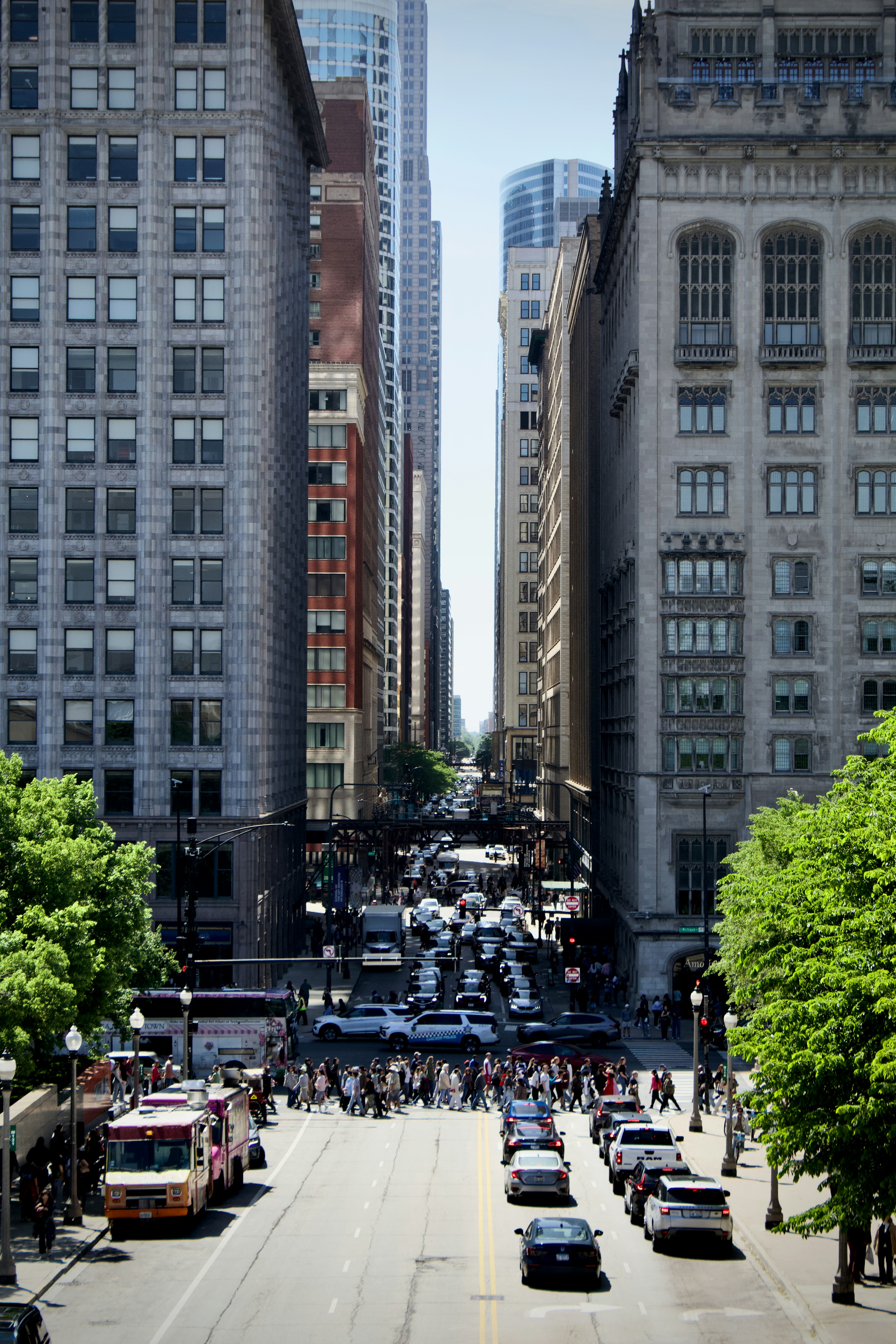 A busy intersection in Chicago with pedestrians crossing the street between tall historic buildings