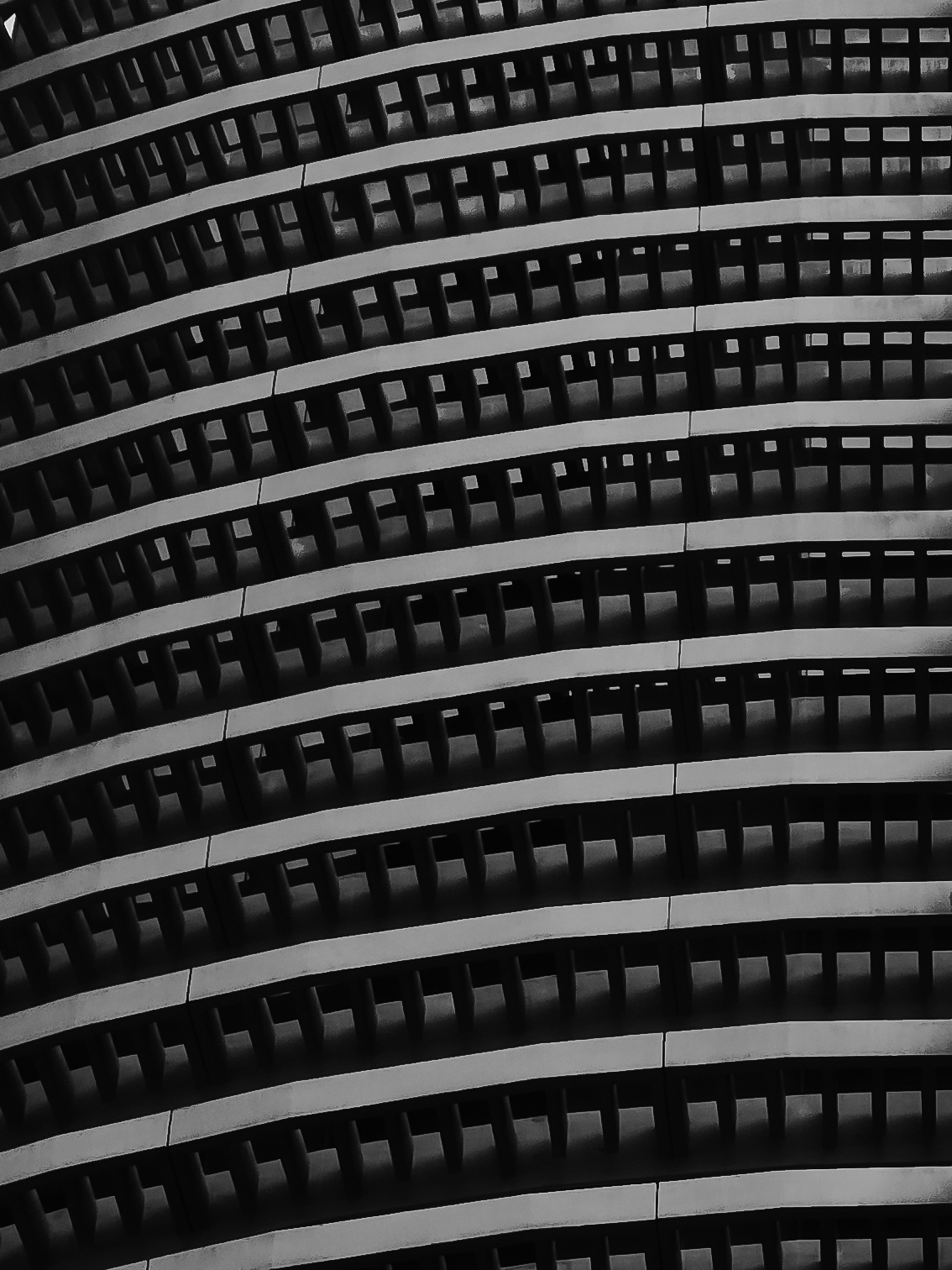 A black and white architectural detail of curved rows of repeating rectangular windows