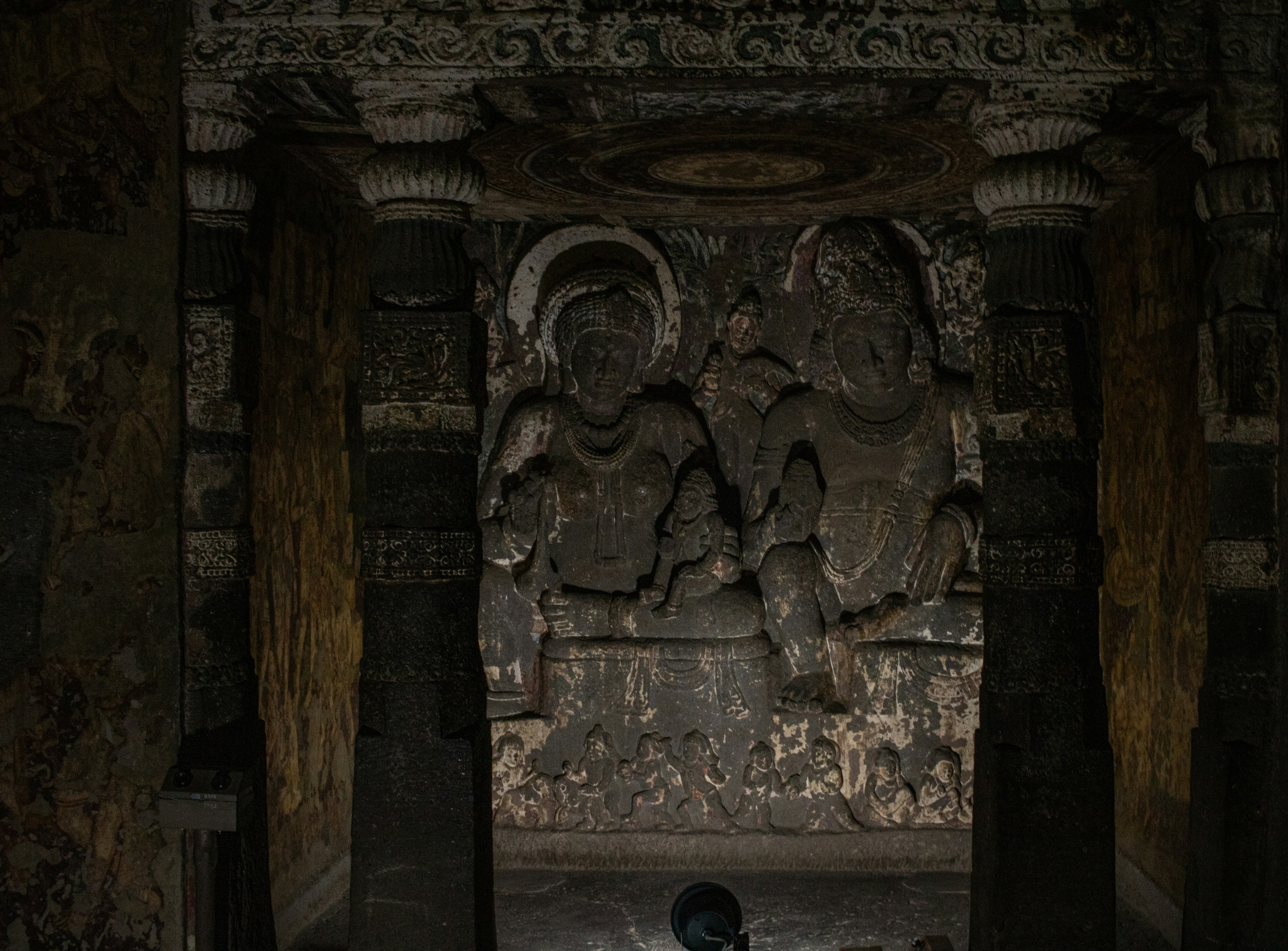 Stone relief of Hārītī and Pañcika in a dimly lit cave at the Ajanta Caves in India