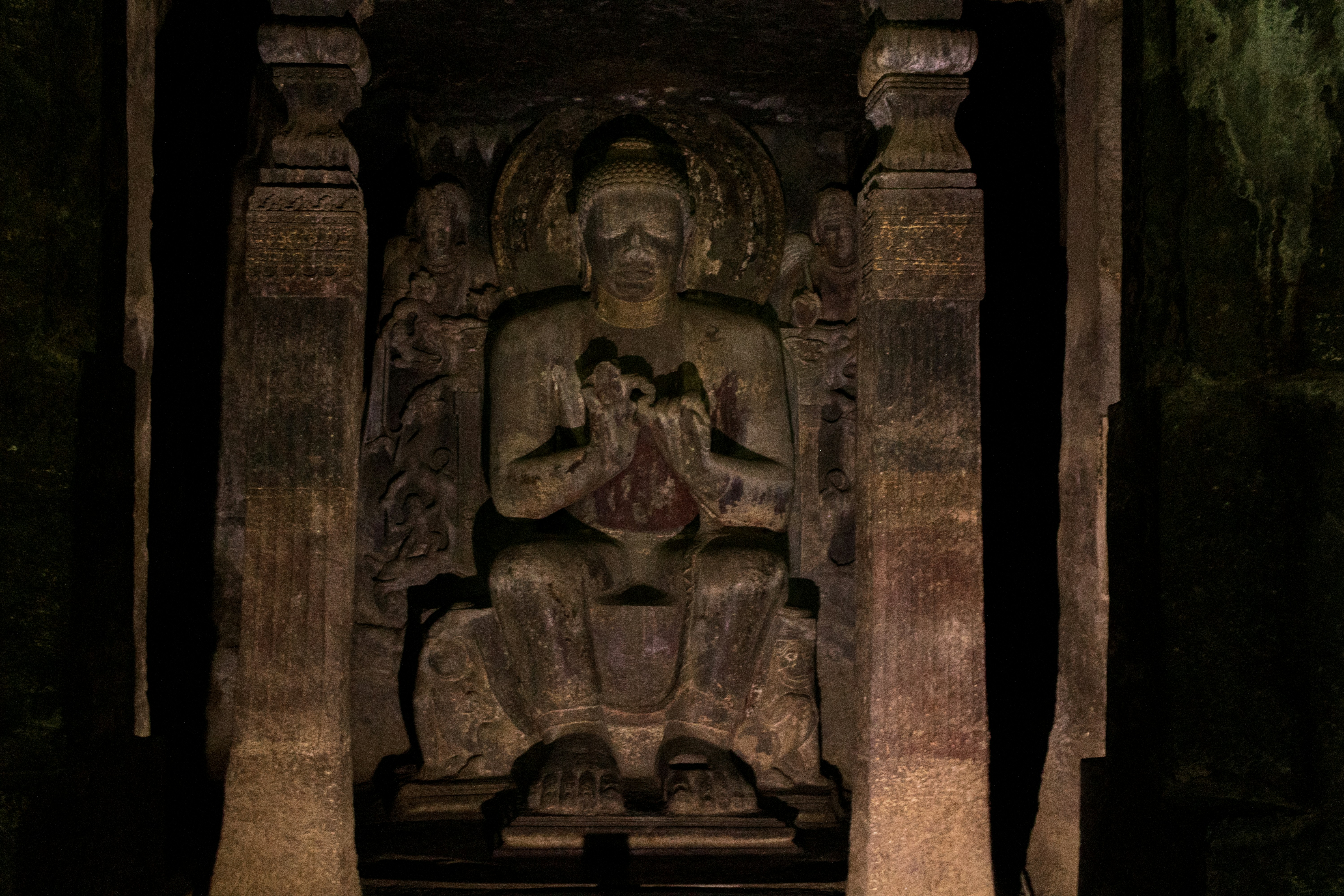 A seated Buddha statue carved into the rock wall of the Ajanta Caves in India