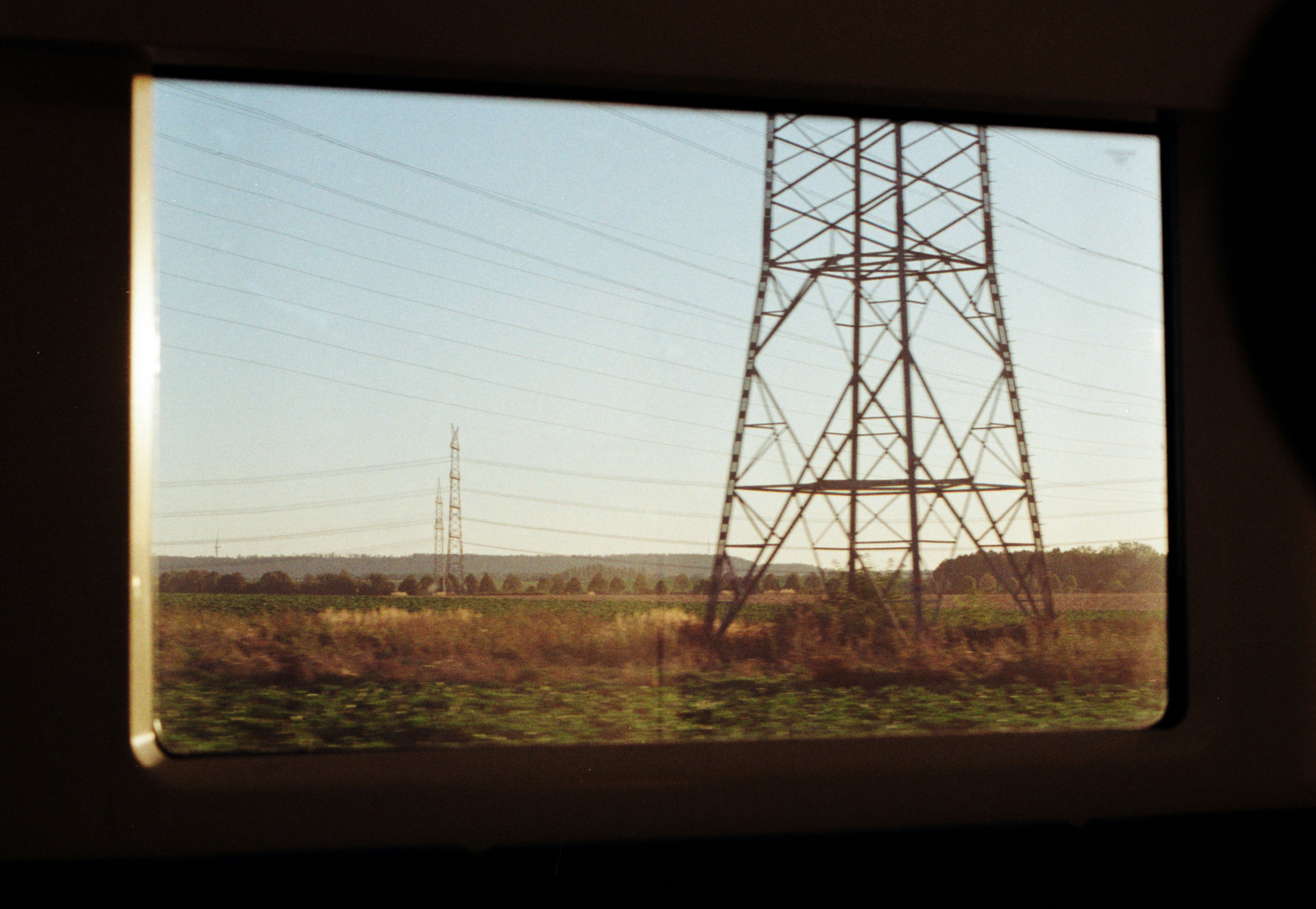 Ein Blick auf einen Metallmast auf einem Feld durch ein Zugfenster