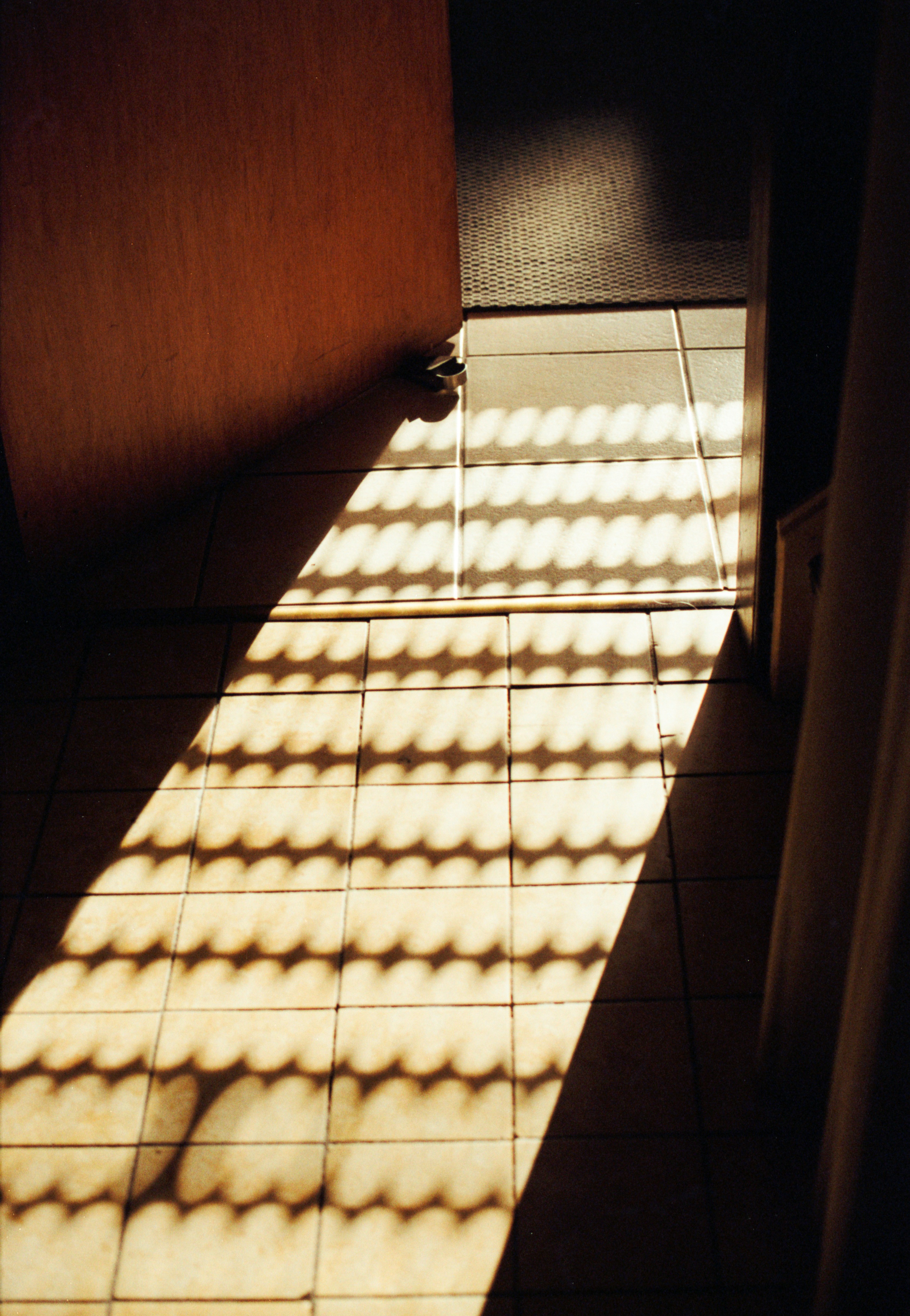 Sonnenlicht warf einen gemusterten Schatten über den gefliesten Boden durch eine offene Tür
