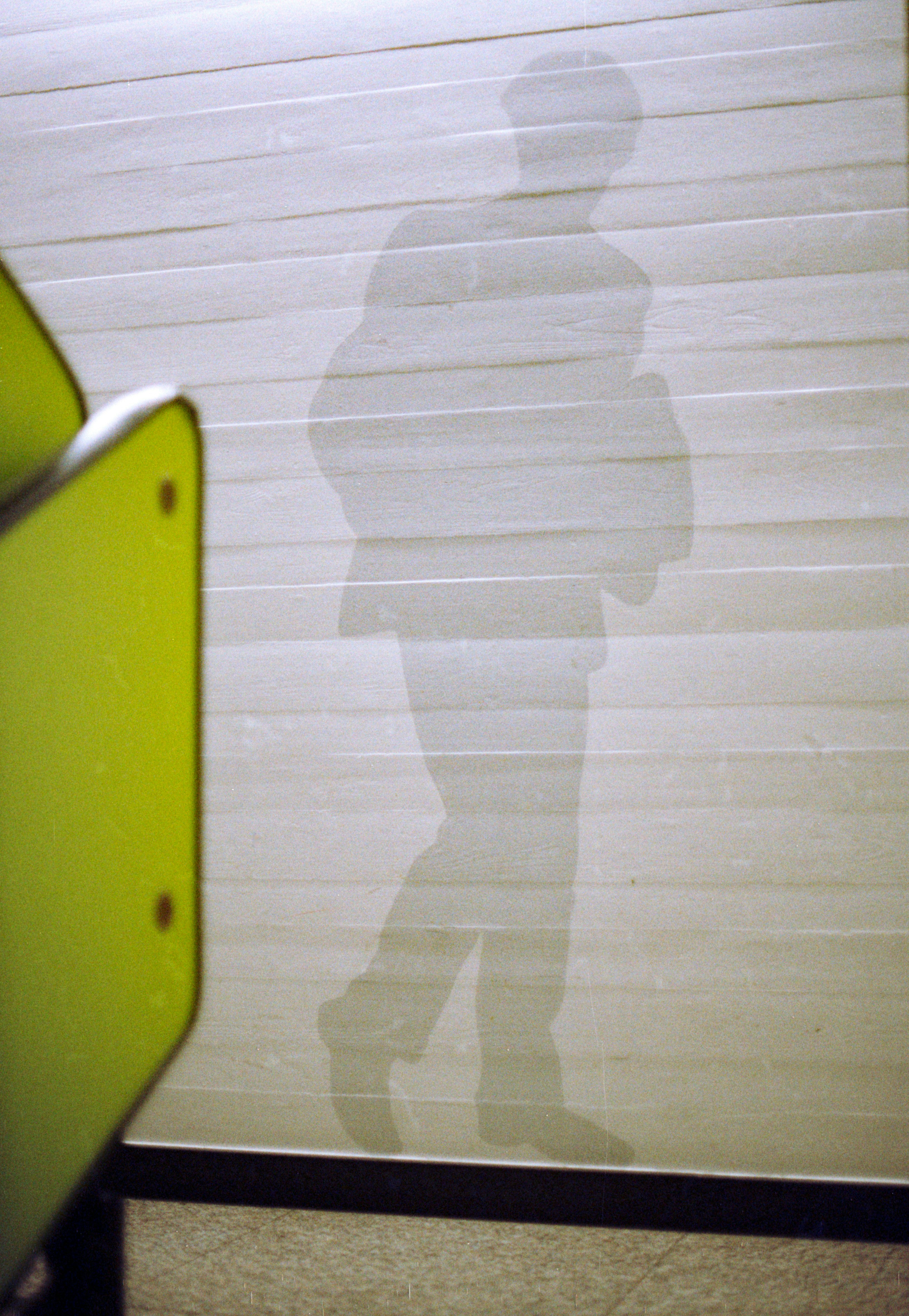 Eine Silhouette einer Person, die an einer hellen Wand mit horizontalen Paneelen entlangläuft