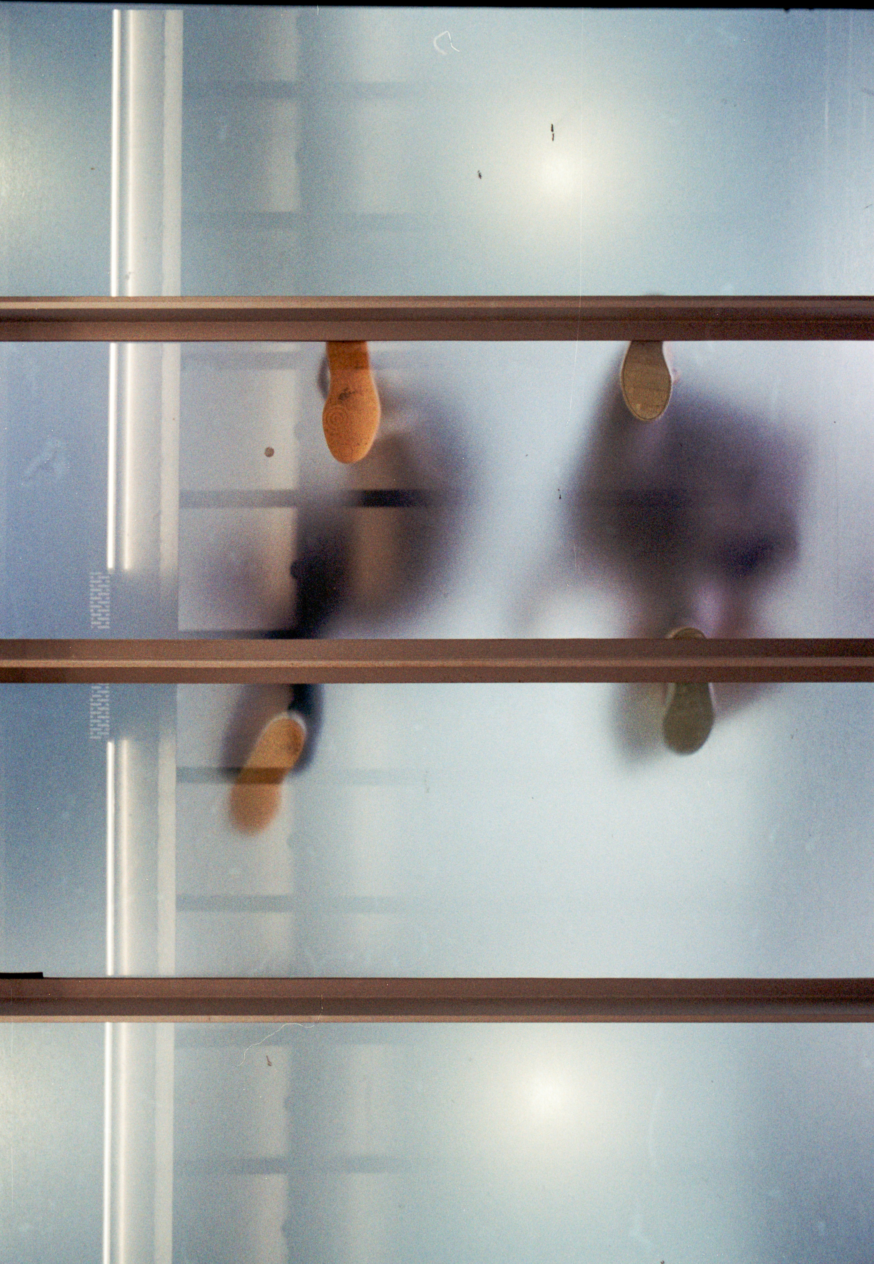 Silhouetten von Menschen, die auf einem mattierten Glasboden gehen, von unten gesehen