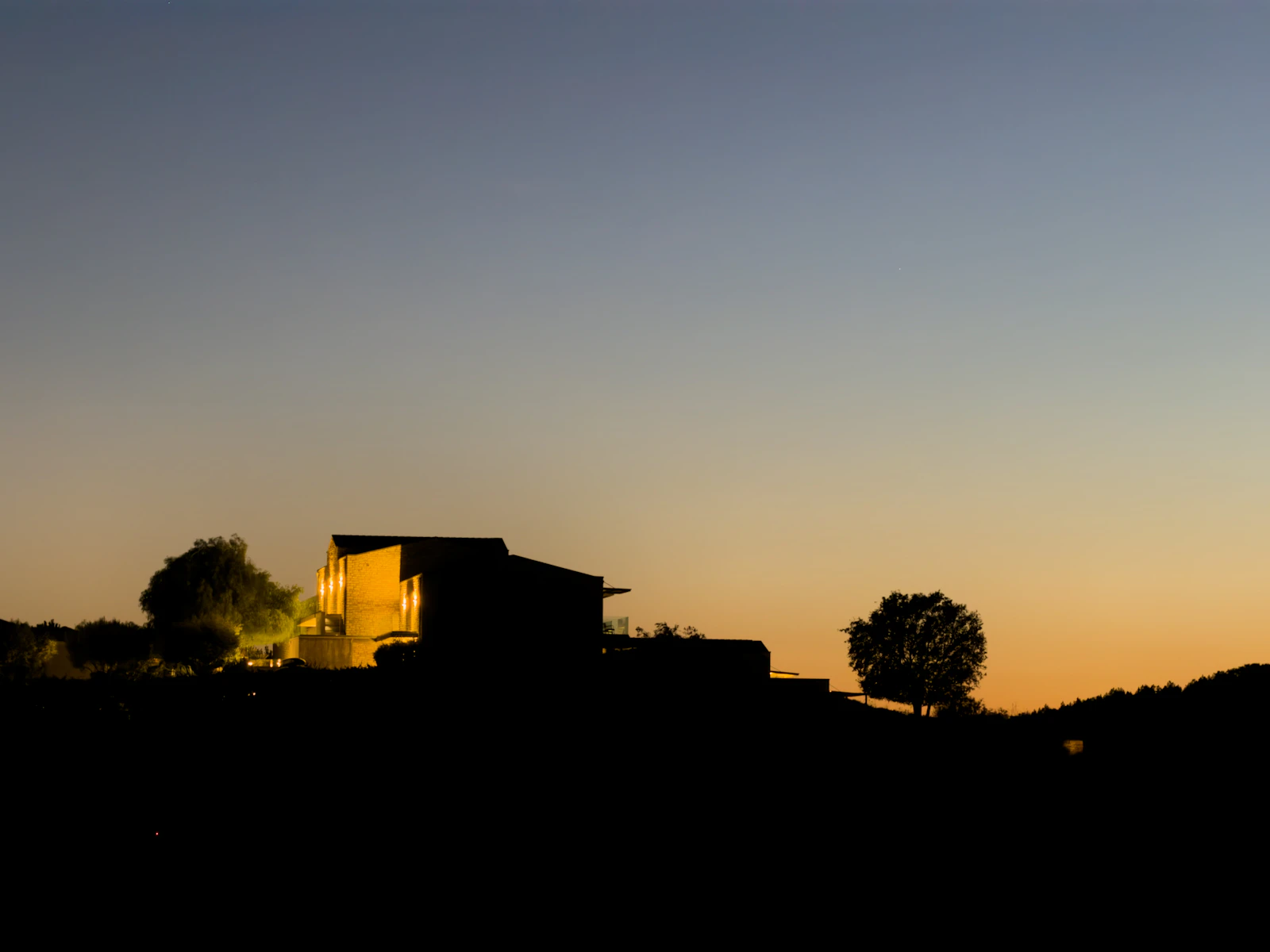 House with warmly lit windows at dusk