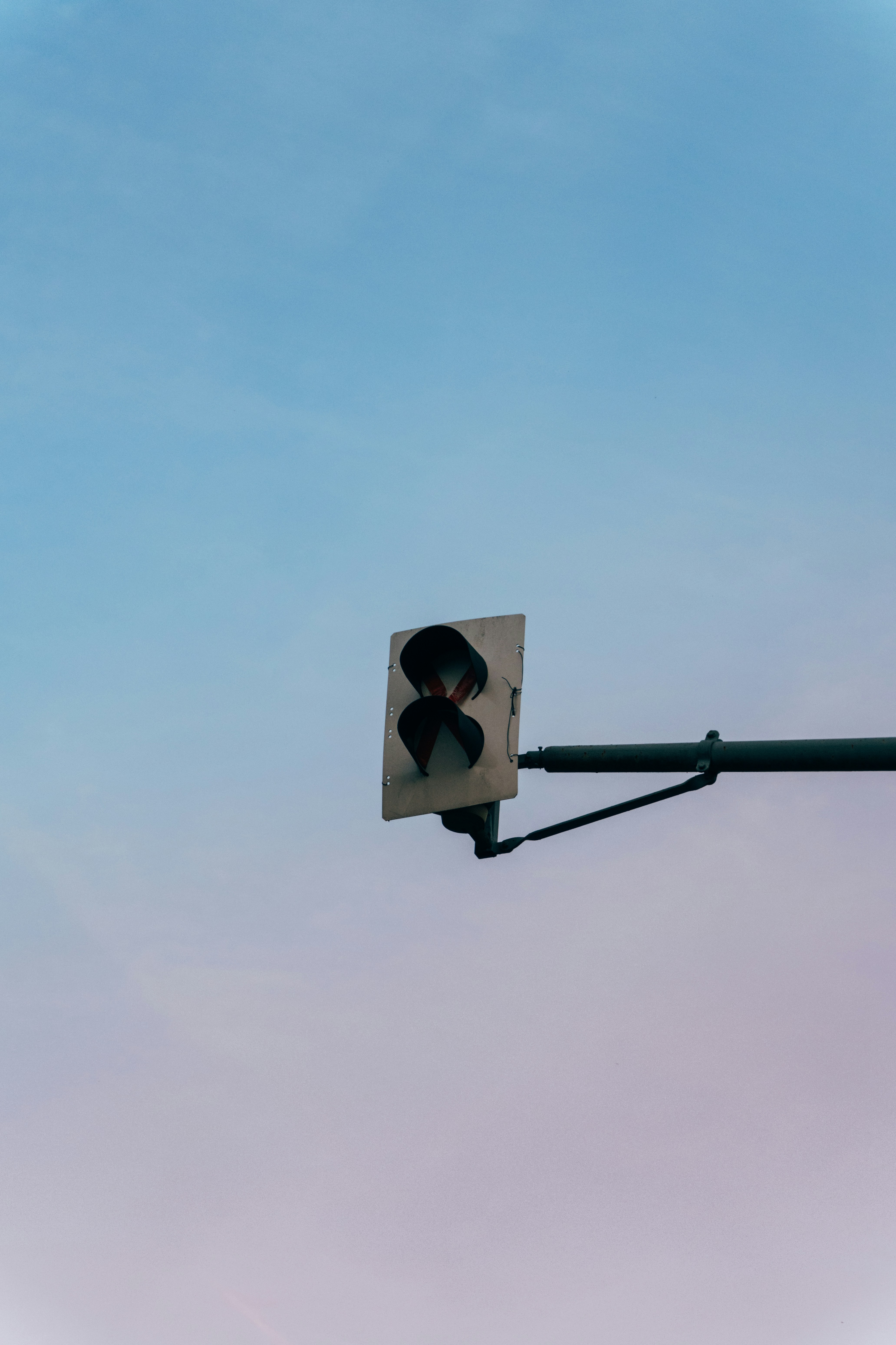 A traffic signal with a red X symbol against a clear blue sky