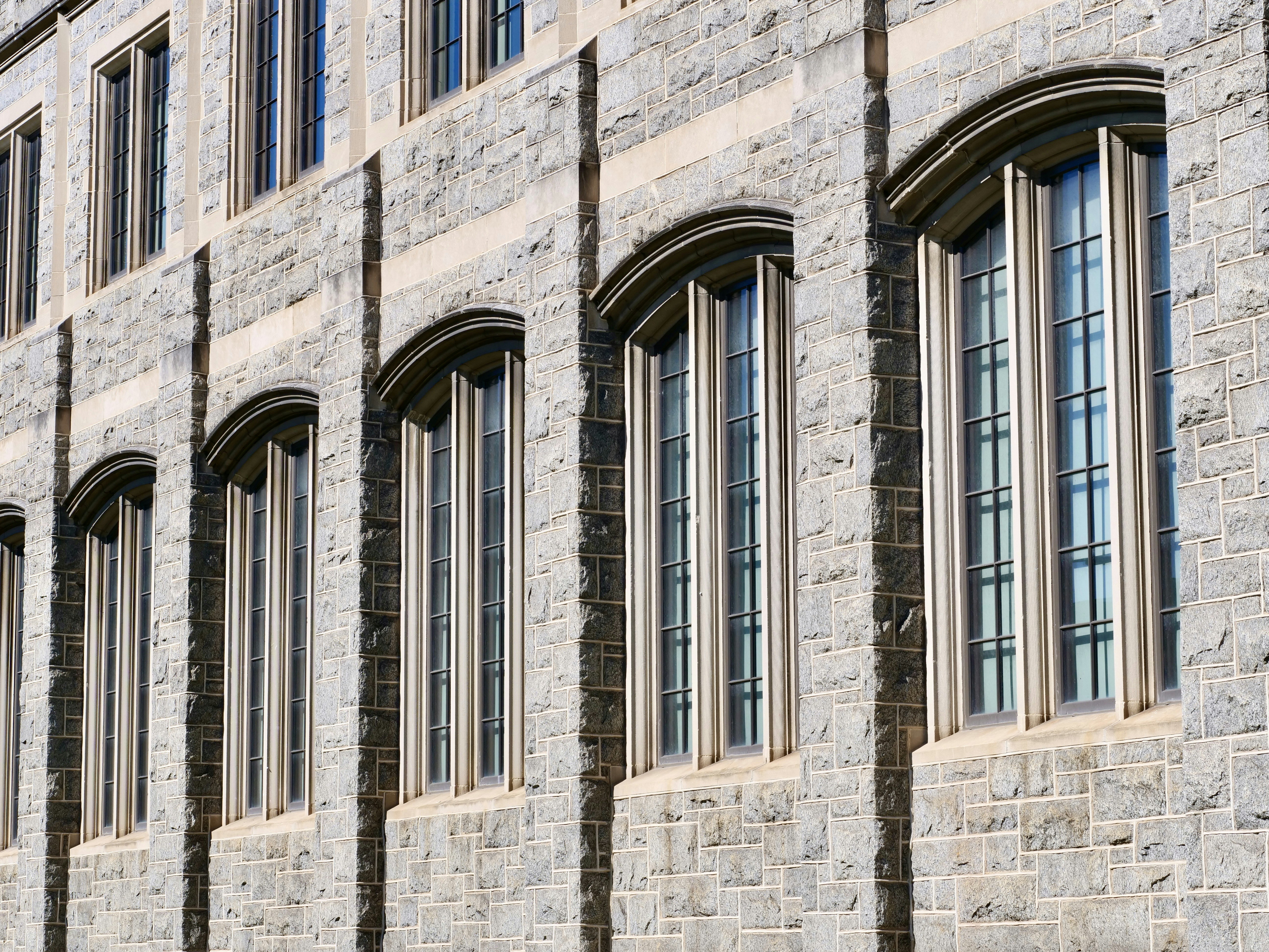 A stone facade with arched windows on a building exterior in bright sunlight
