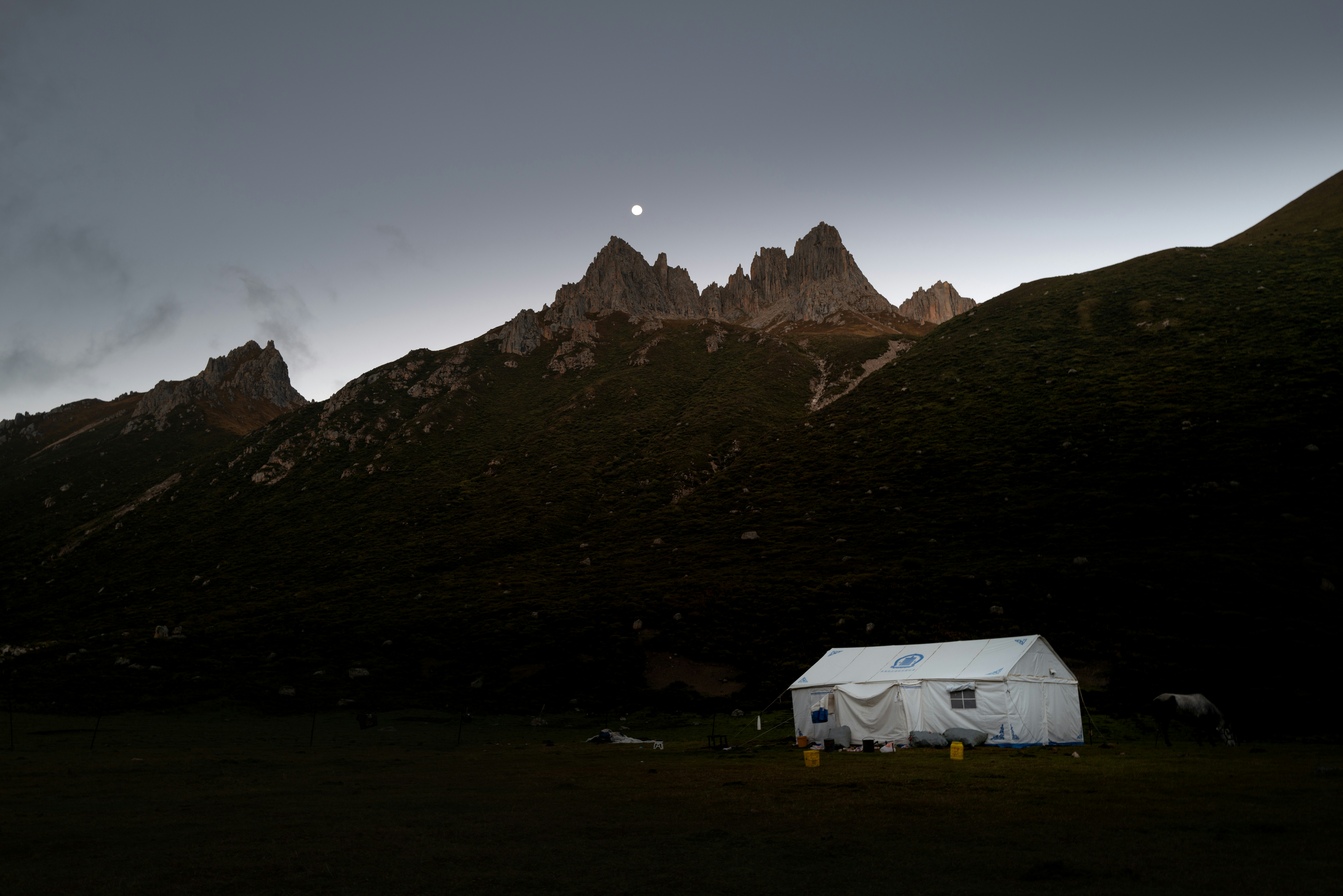 White tent beneath jagged mountain peaks - Free Photo on Unsplash