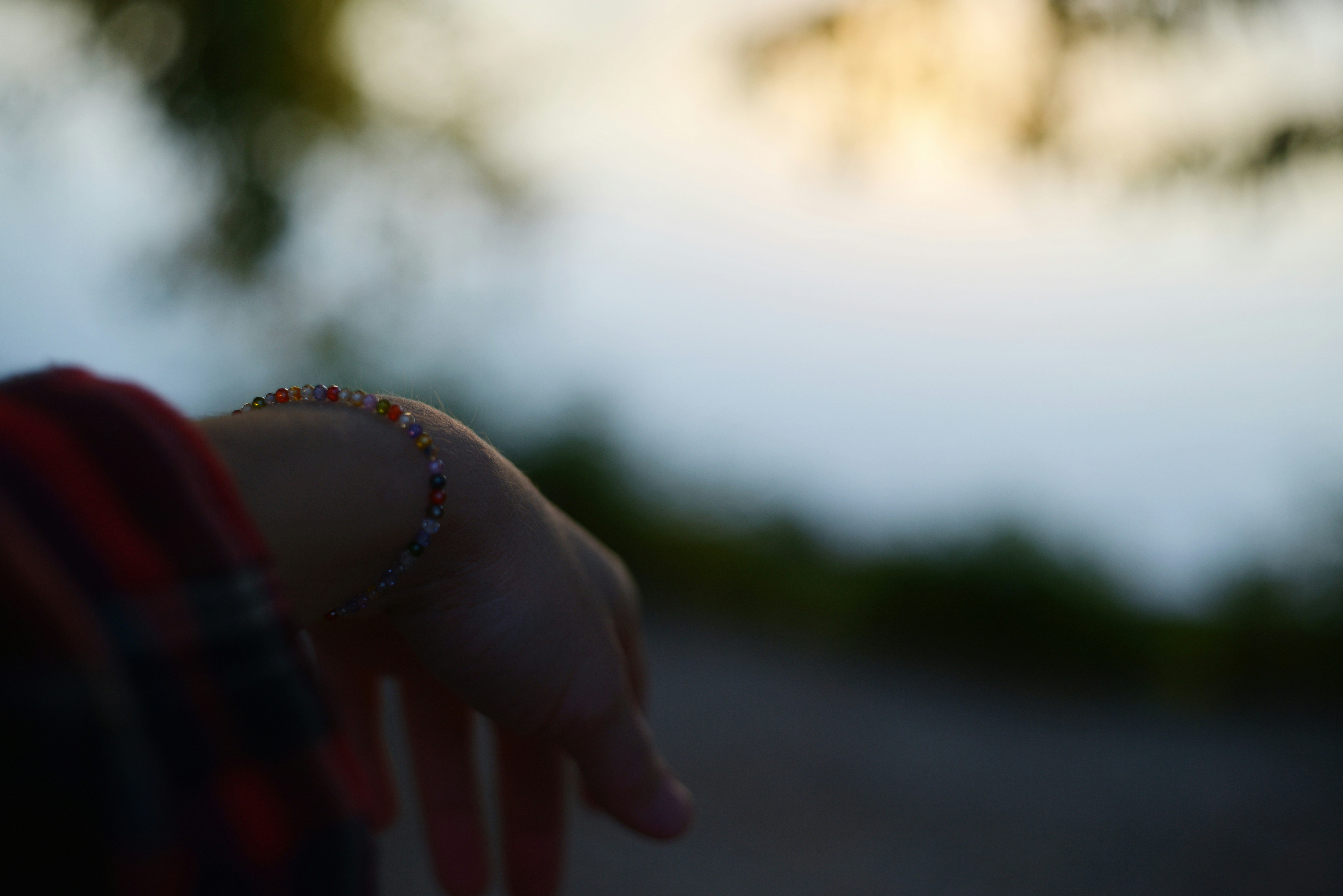 Une personne portant un bracelet coloré à perles au poignet sur un fond doux en bokeh