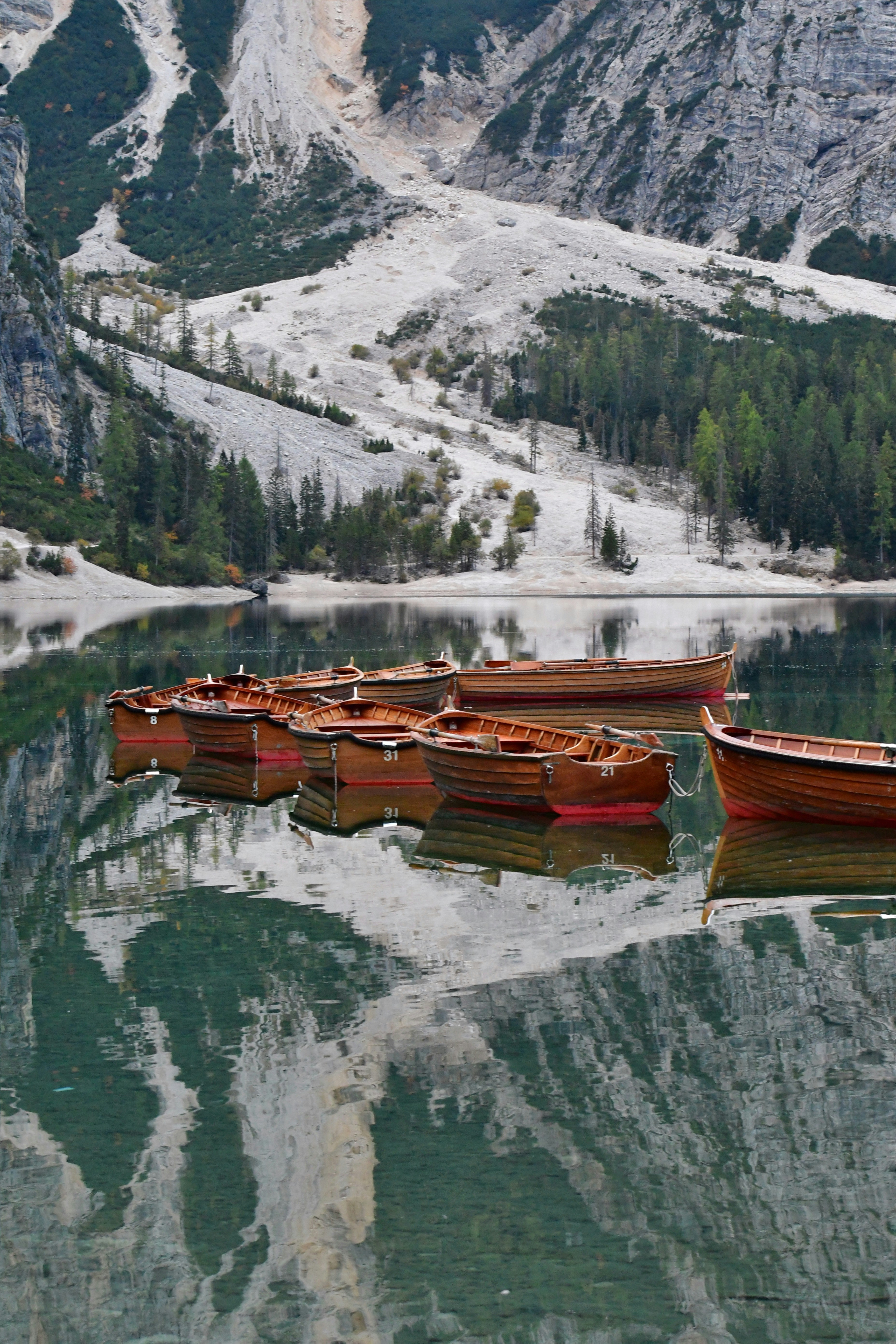 Botes de remos de madera amarrados en las aguas tranquilas del Lago di Braies con reflejos montañosos