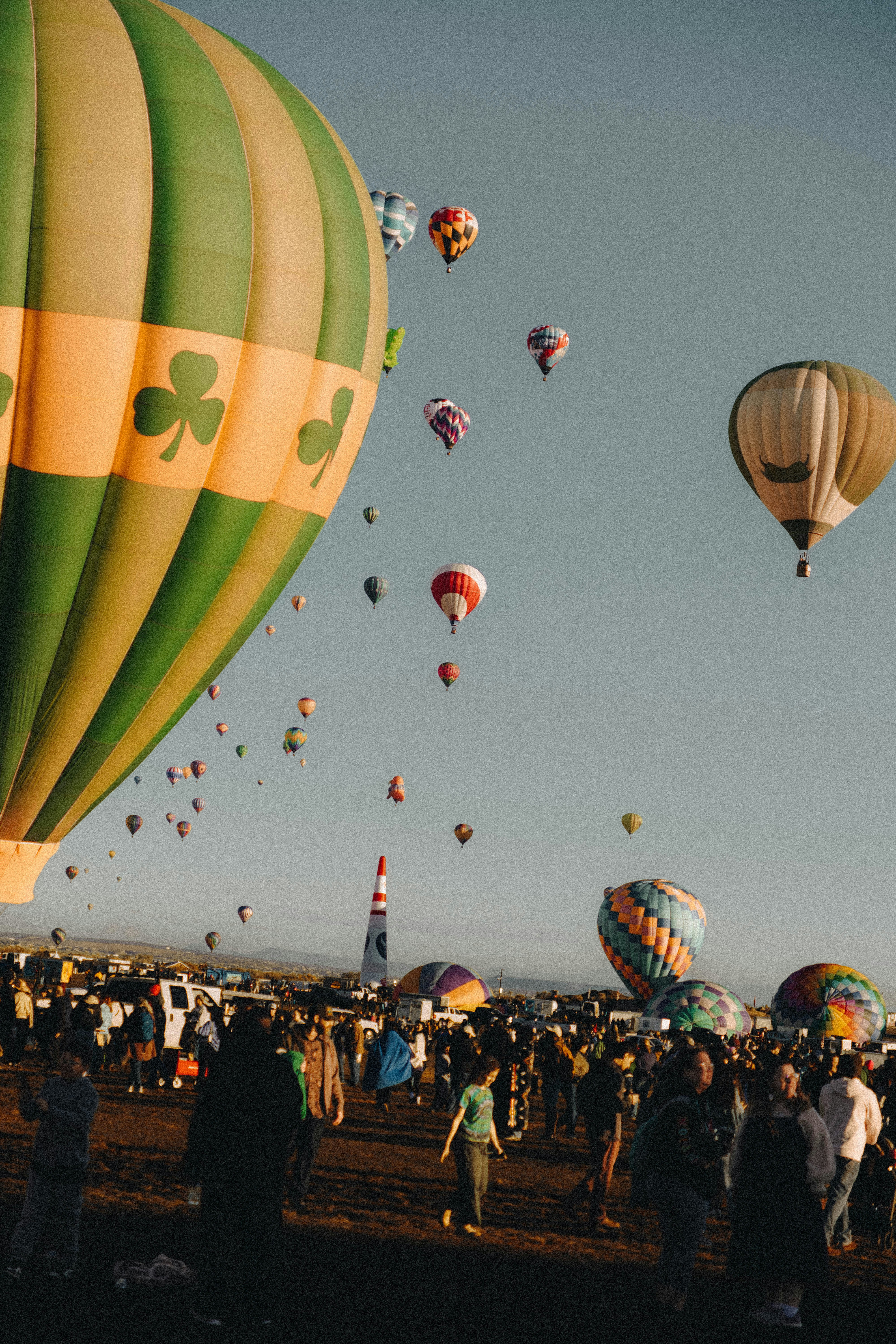 Molte mongolfiere colorate fluttuano in un cielo limpido sopra una grande folla di persone
