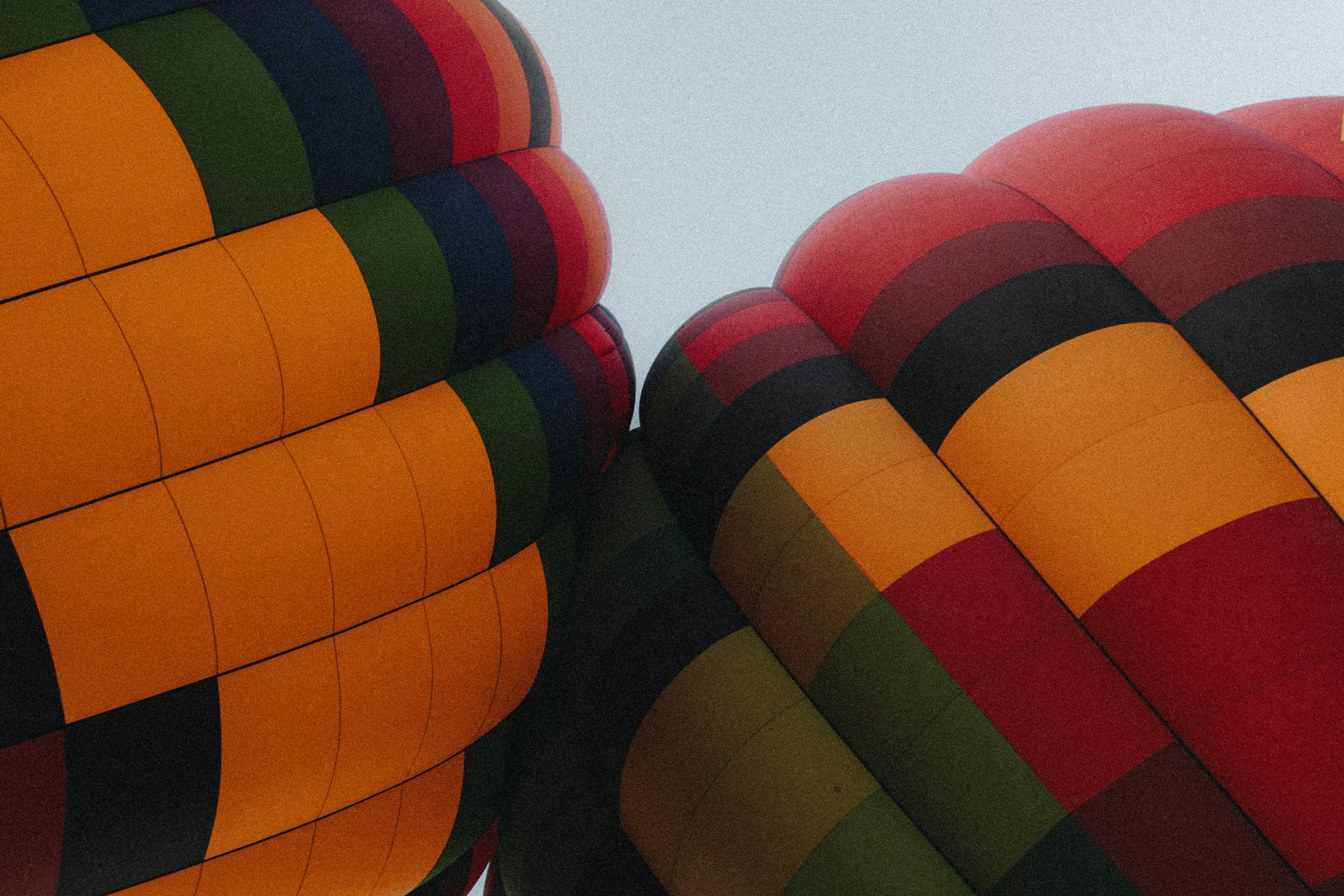 Due coloriti involucri di mongolfiere con un motivo geometrico contro un cielo pallido