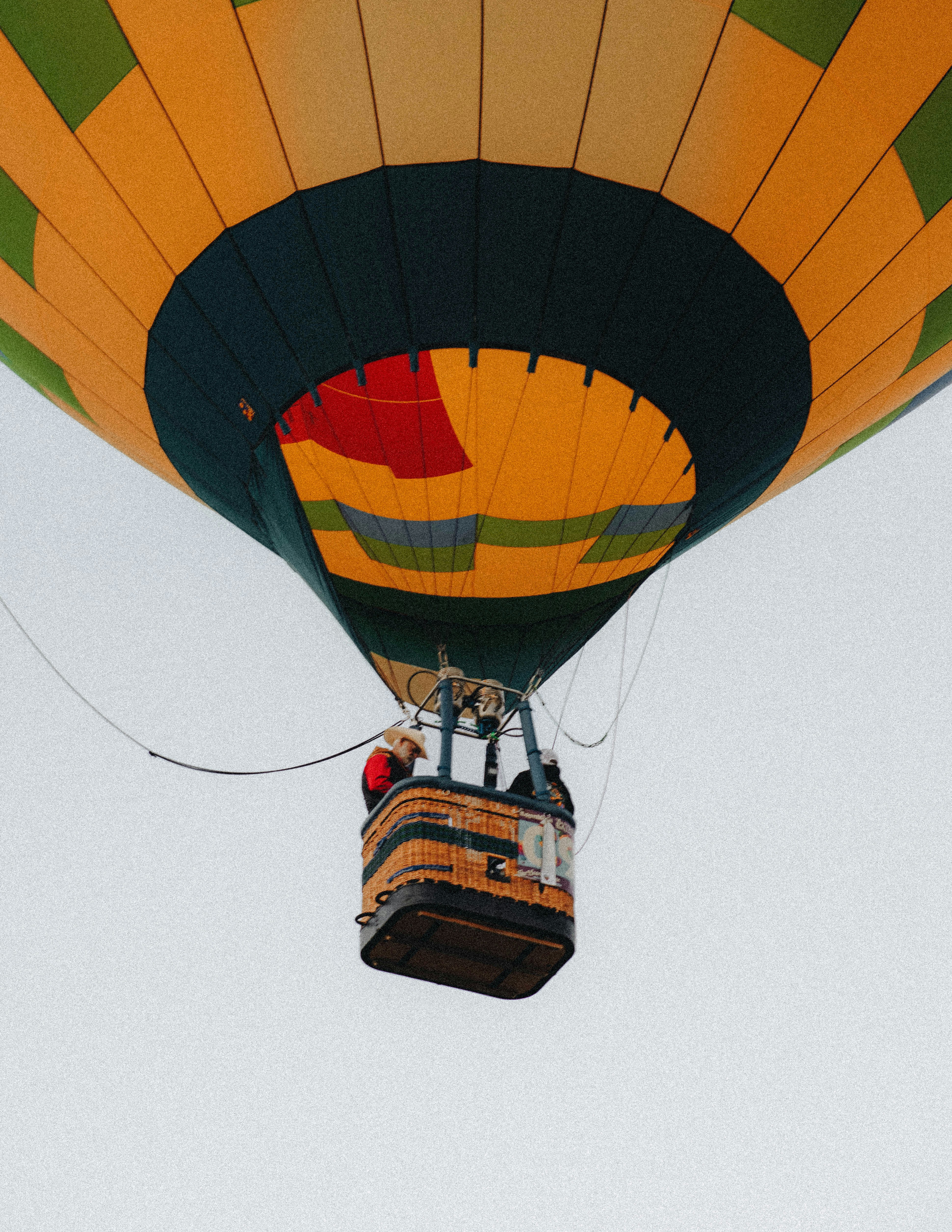 Una mongolfiera colorata con due persone nel cestino di vimini contro un cielo pallido