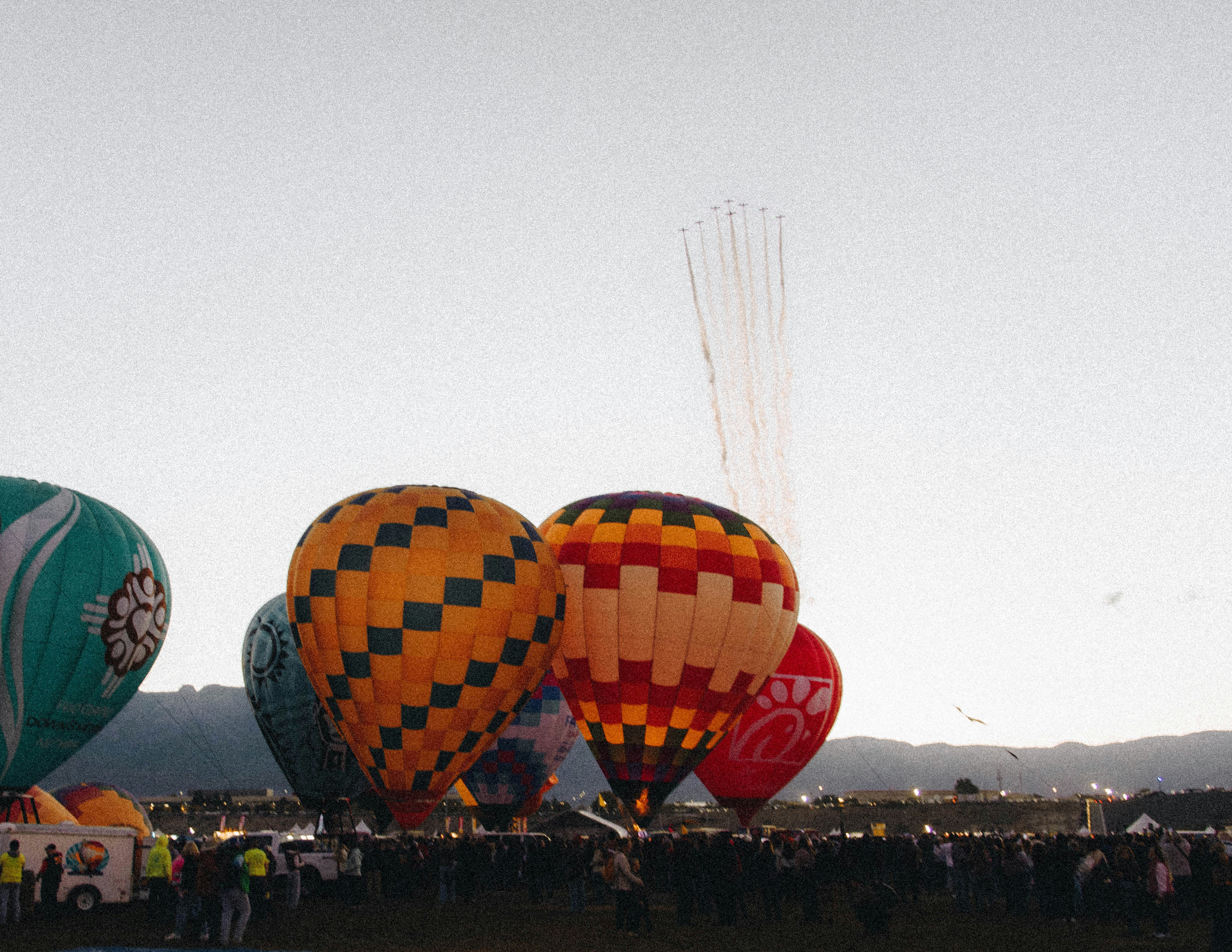 Mongolfiere sopra la folla all'Albuquerque International Balloon Fiesta con scie di jet sopra