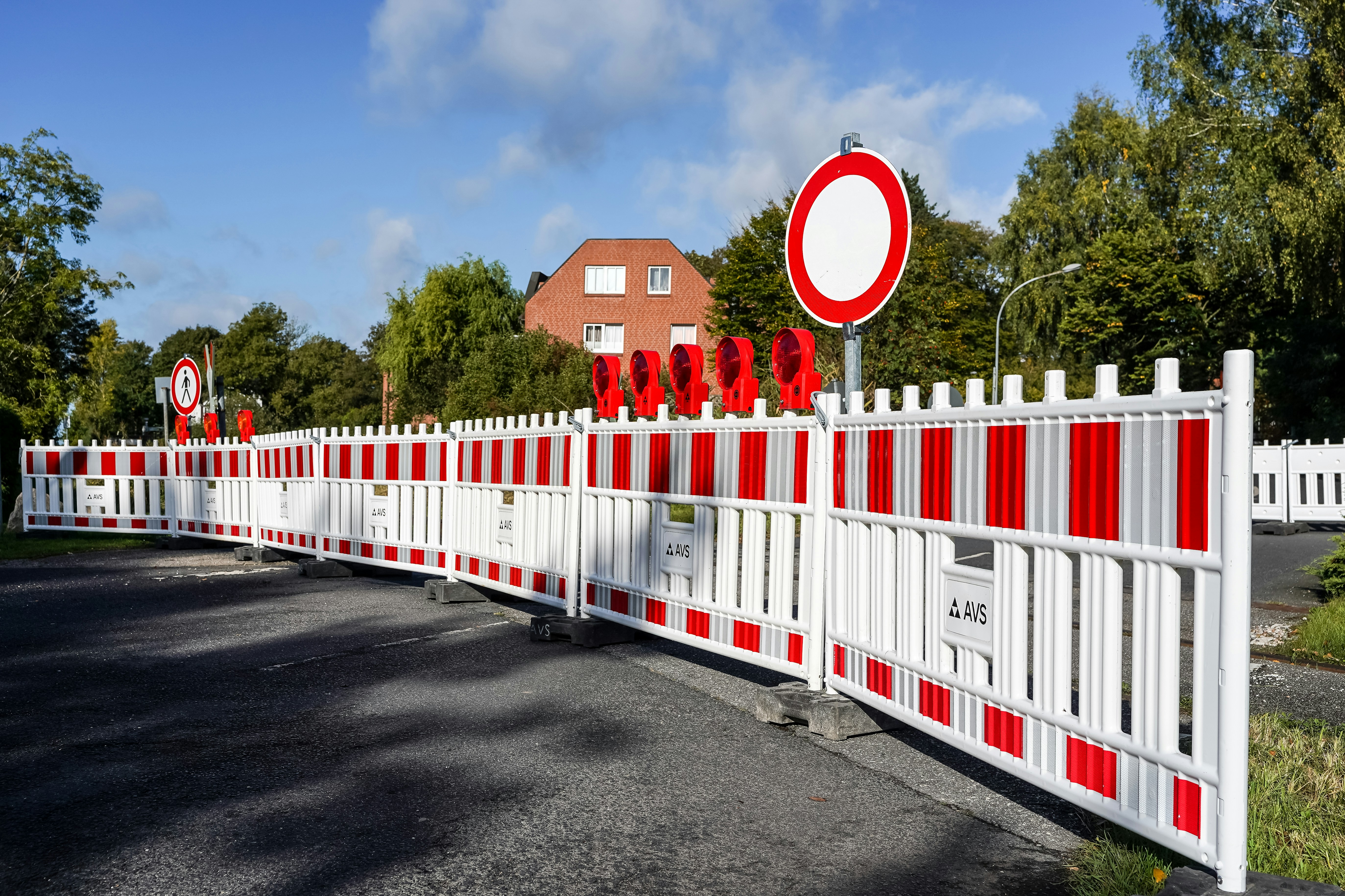 Red and white plastic construction barriers blocking a road with a circular no entry sign