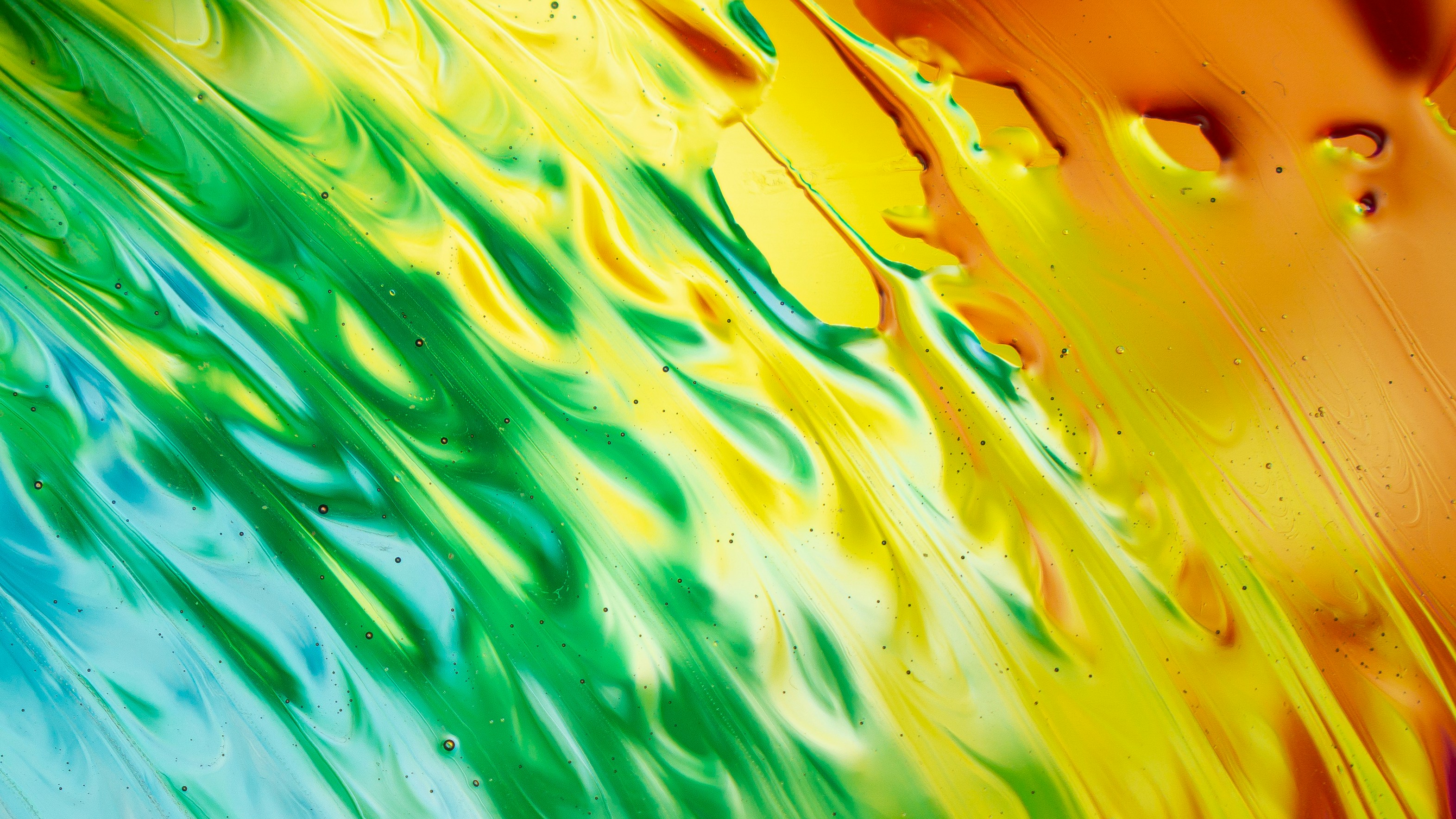 Swirling liquid paint in vibrant shades of blue, green, yellow, and orange