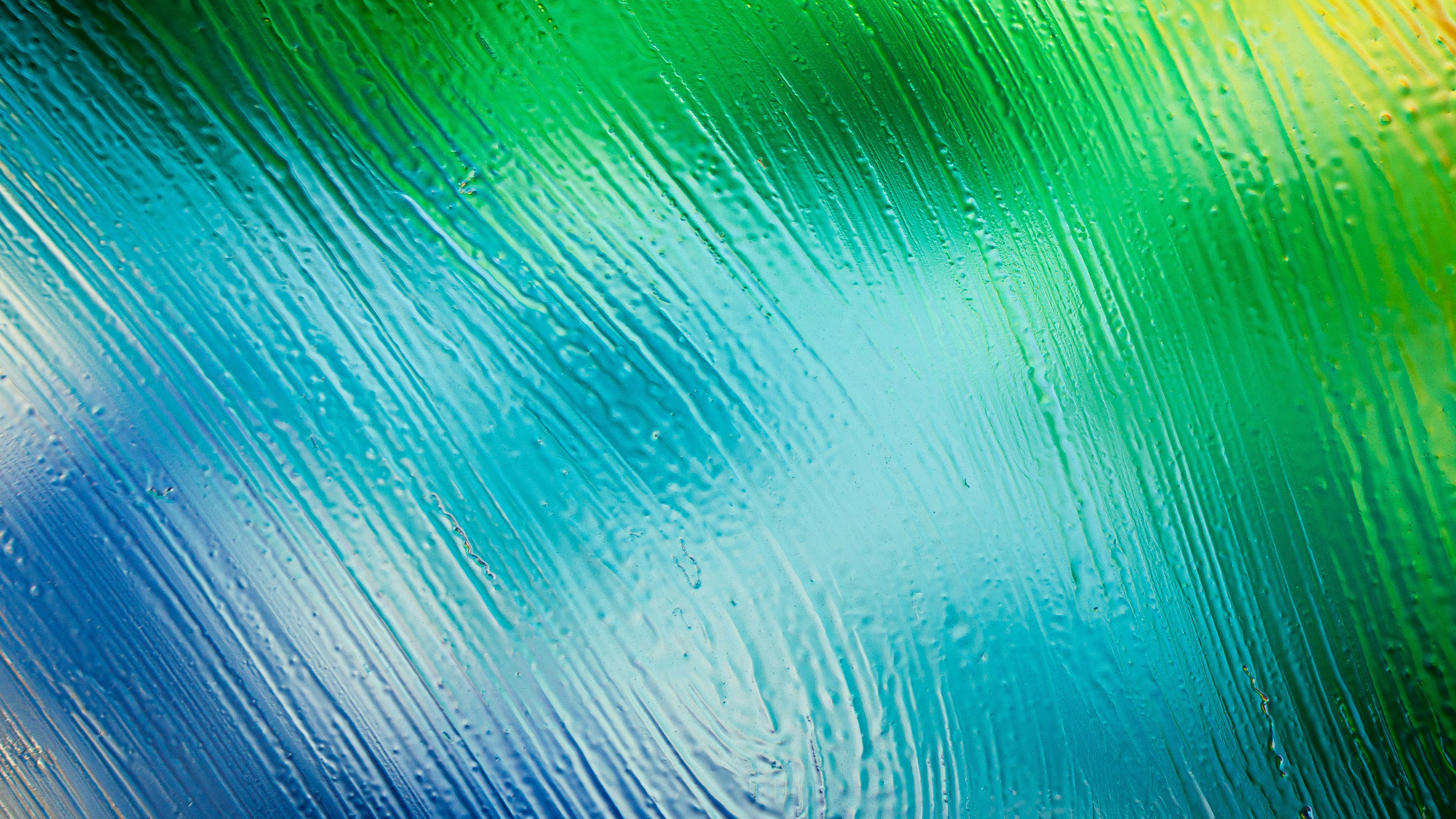 A vibrant abstract texture of diagonal brushstrokes in shades of blue, green, and yellow