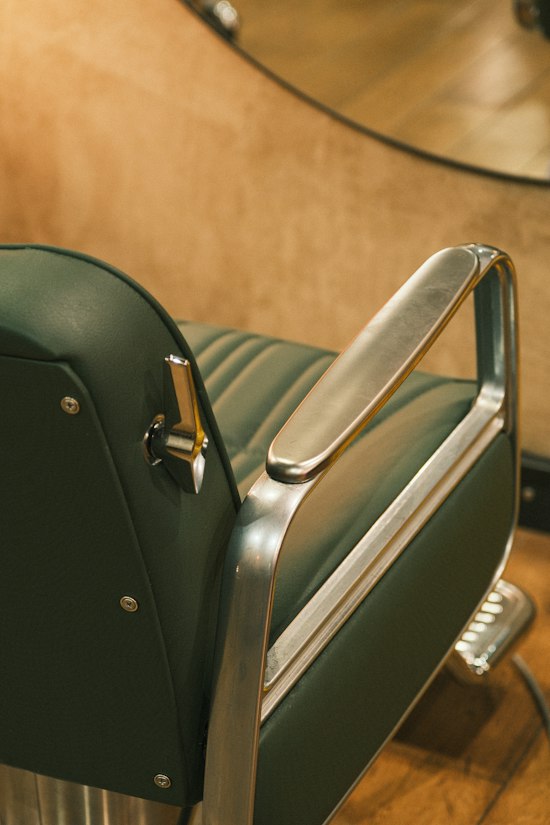 Green leather vintage barber chair with chrome armrests
