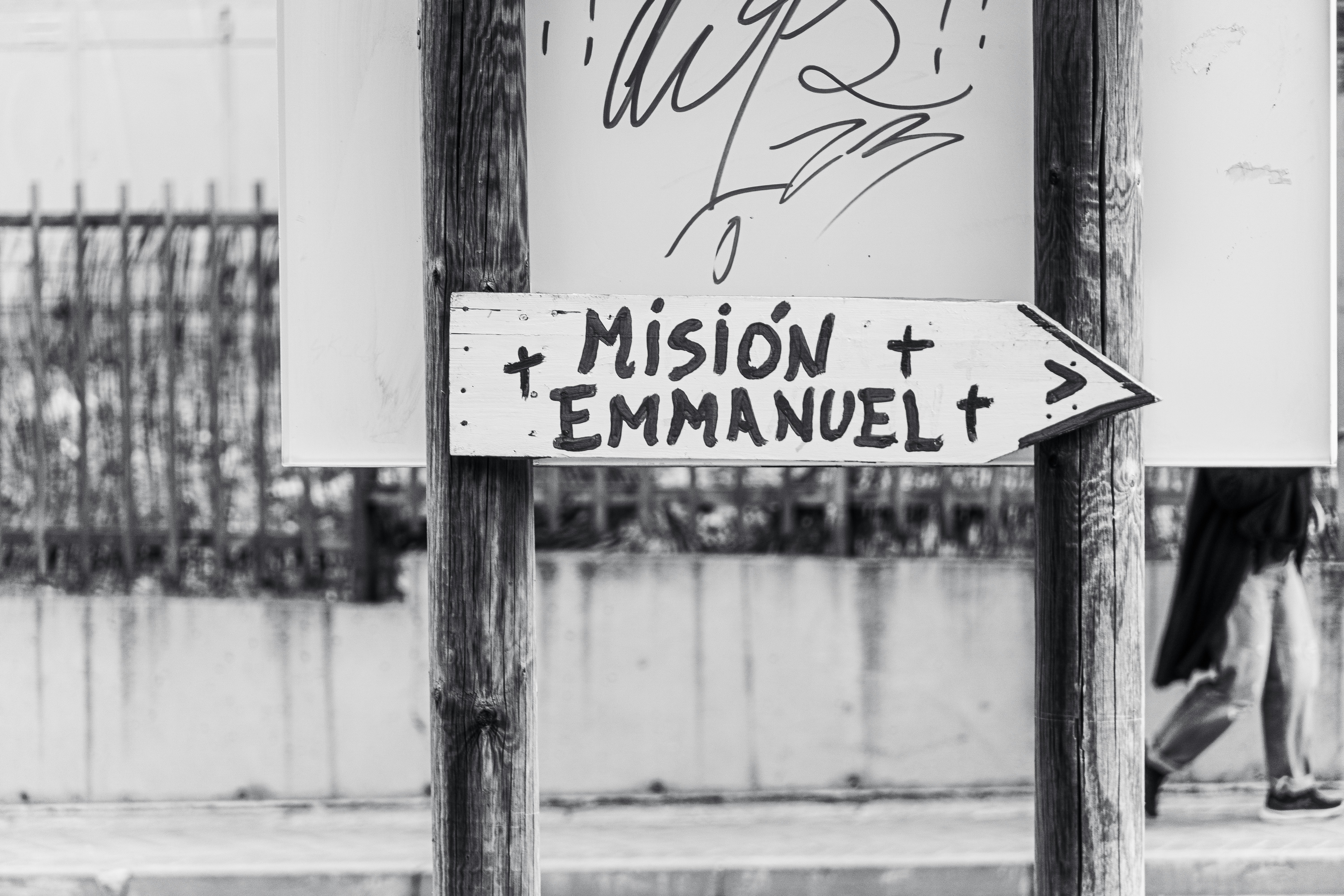 A black and white sign reading Misión Emmanuel with crosses on wooden posts