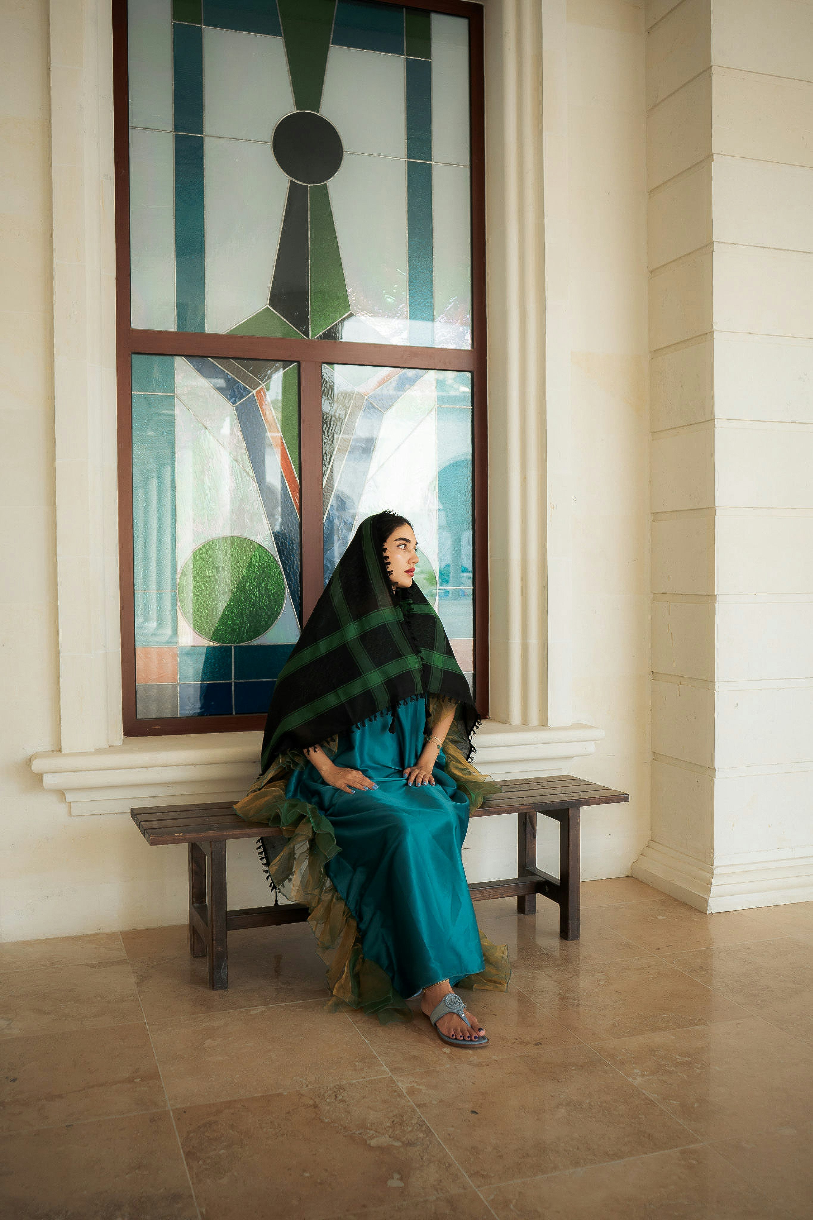 A woman sitting on a wooden bench in front of a large stained glass window