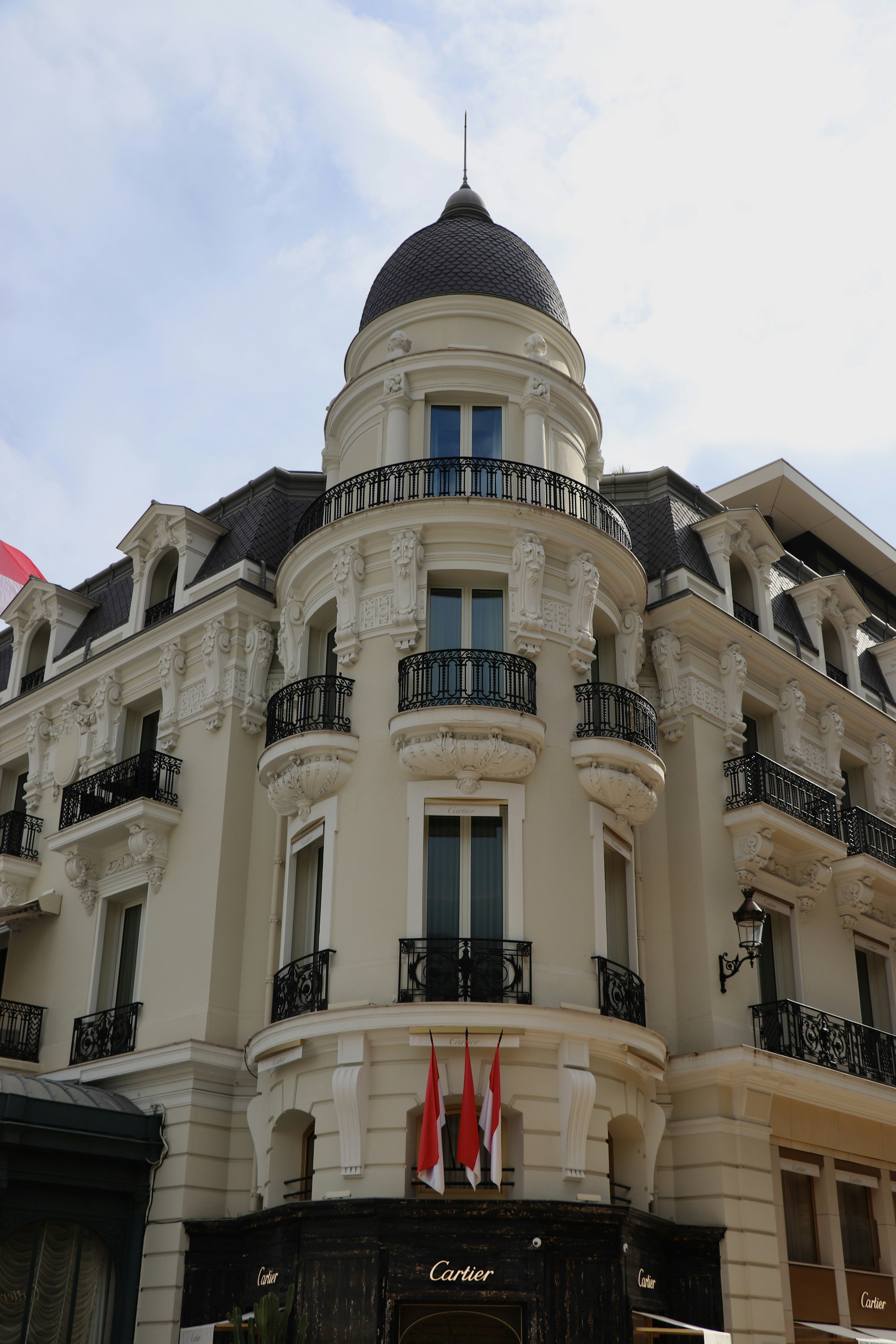 The ornate corner facade of the Cartier building in Monte Carlo with balconies and red flags
