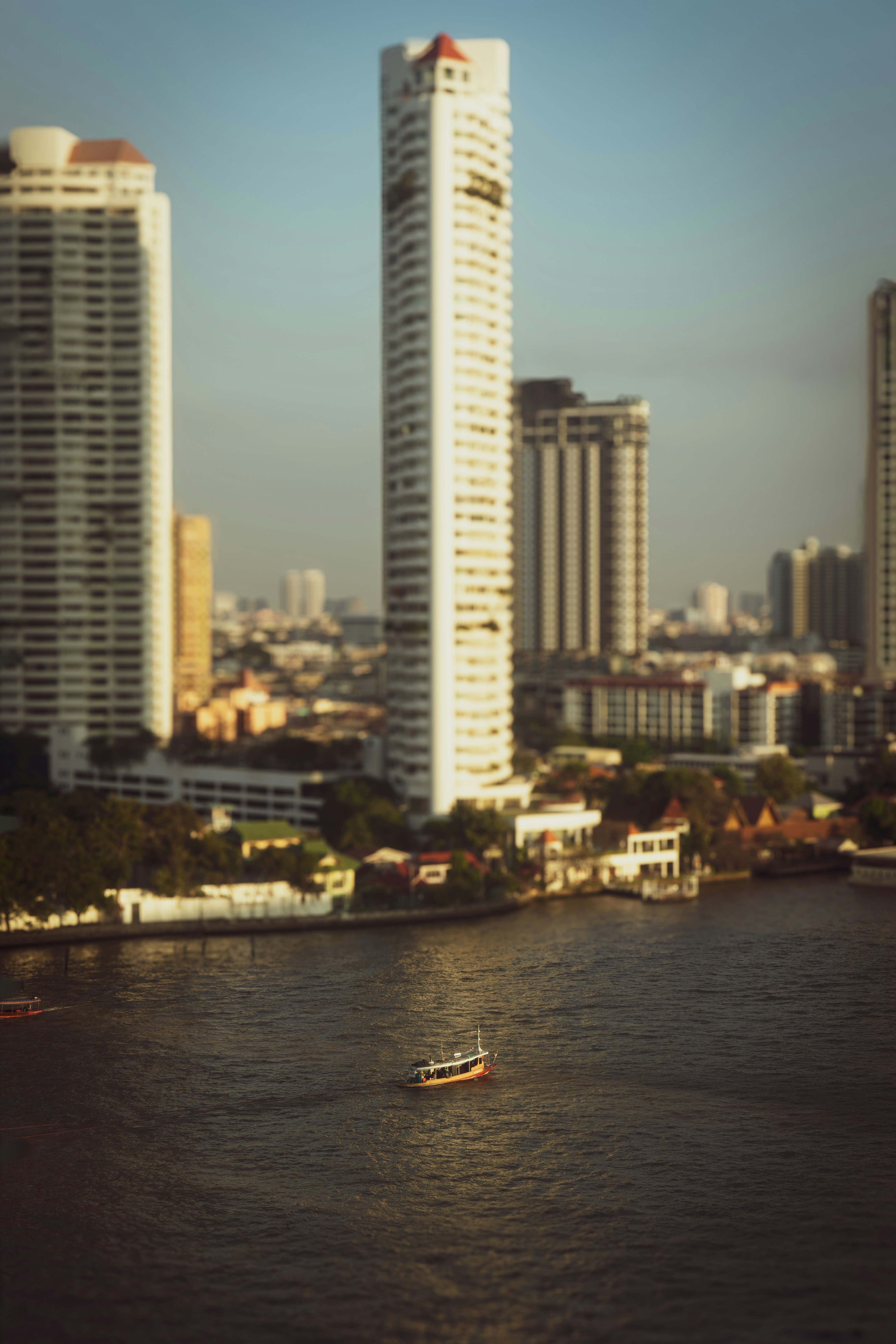Un petit bateau sur la rivière Chao Phraya à Bangkok, avec de hauts gratte-ciel en arrière-plan