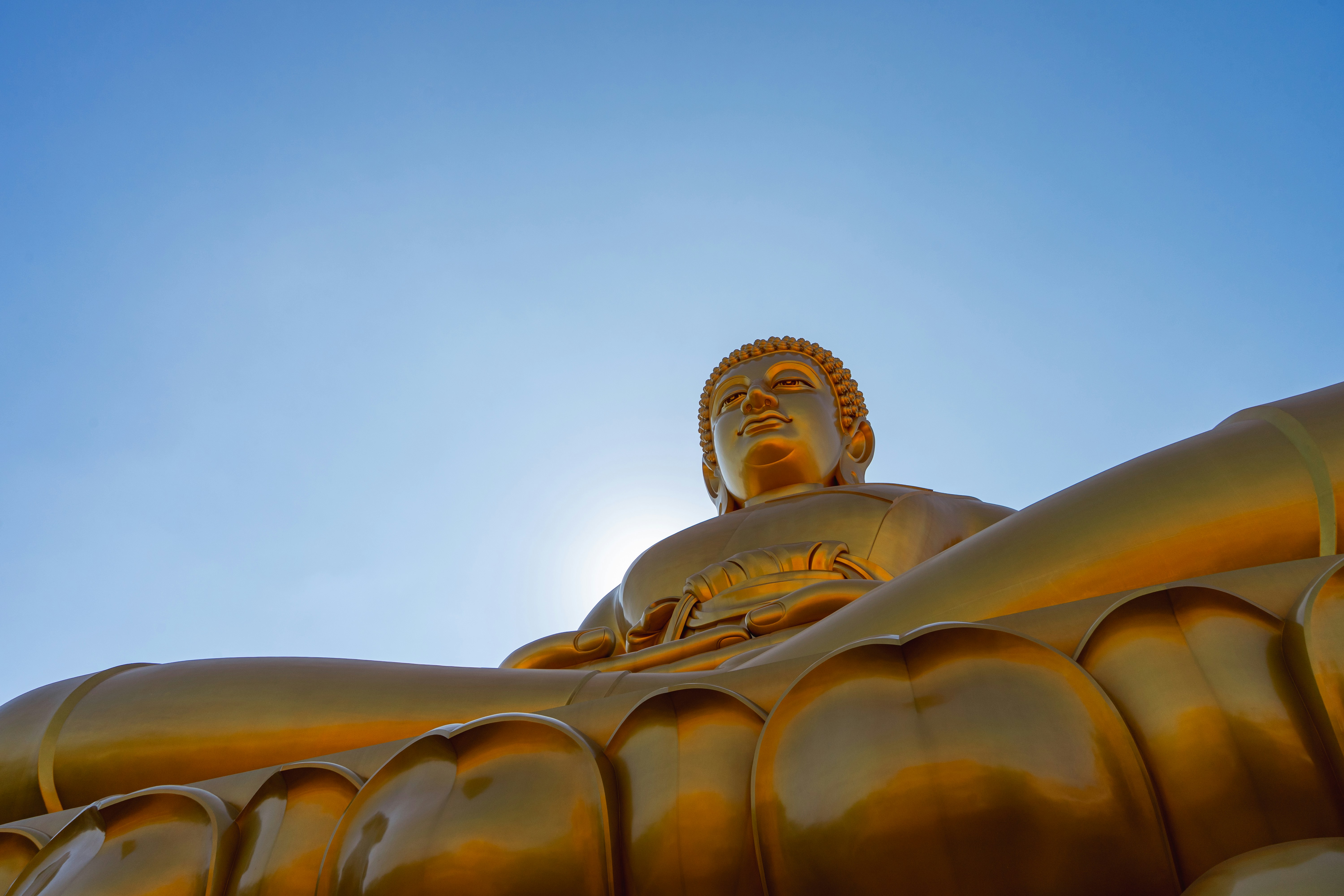 Vue basse d’une statue géante de Bouddha doré sur un ciel bleu clair