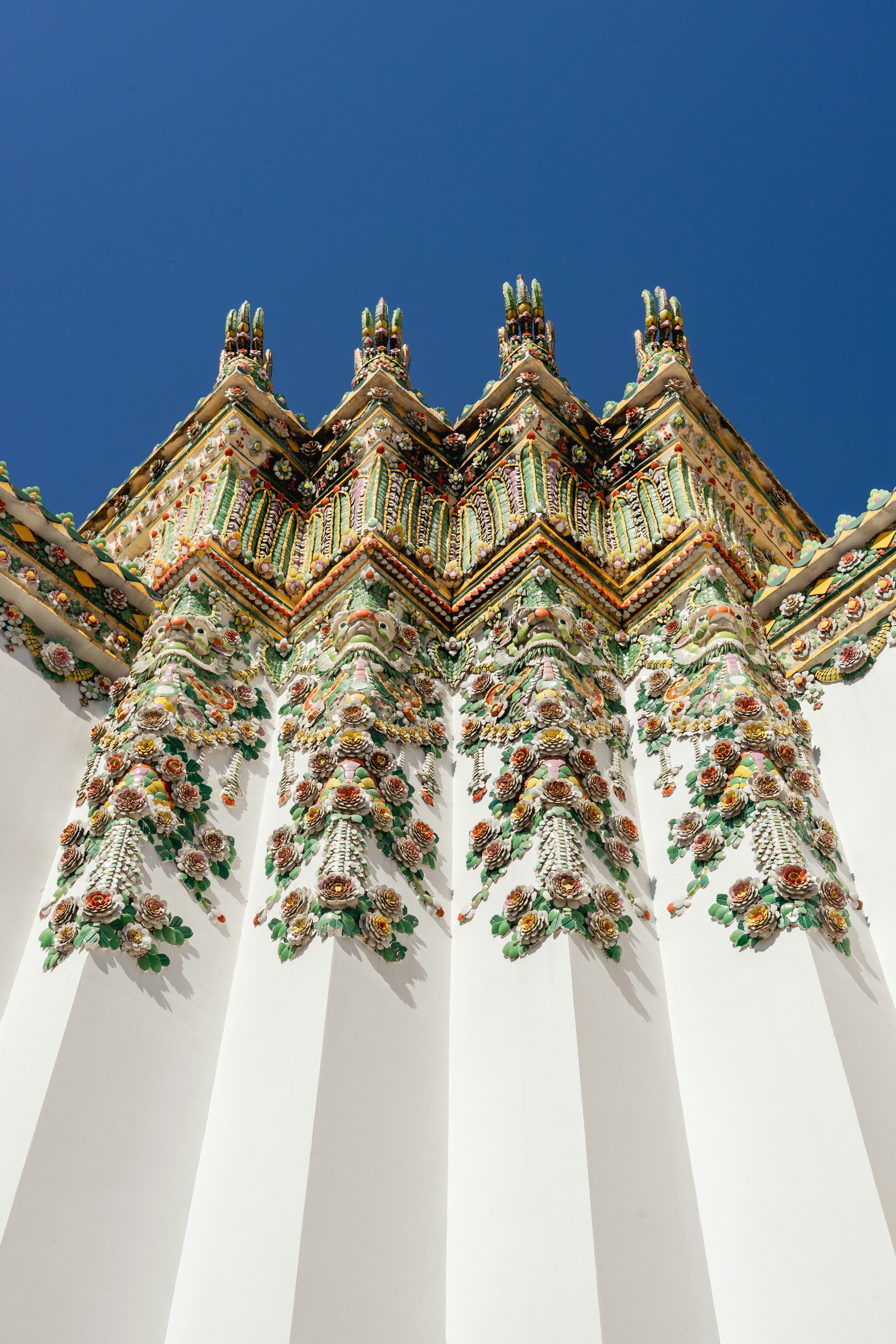 Les décorations florales en céramique ornées sur un mur blanc de temple à Bangkok, en Thaïlande