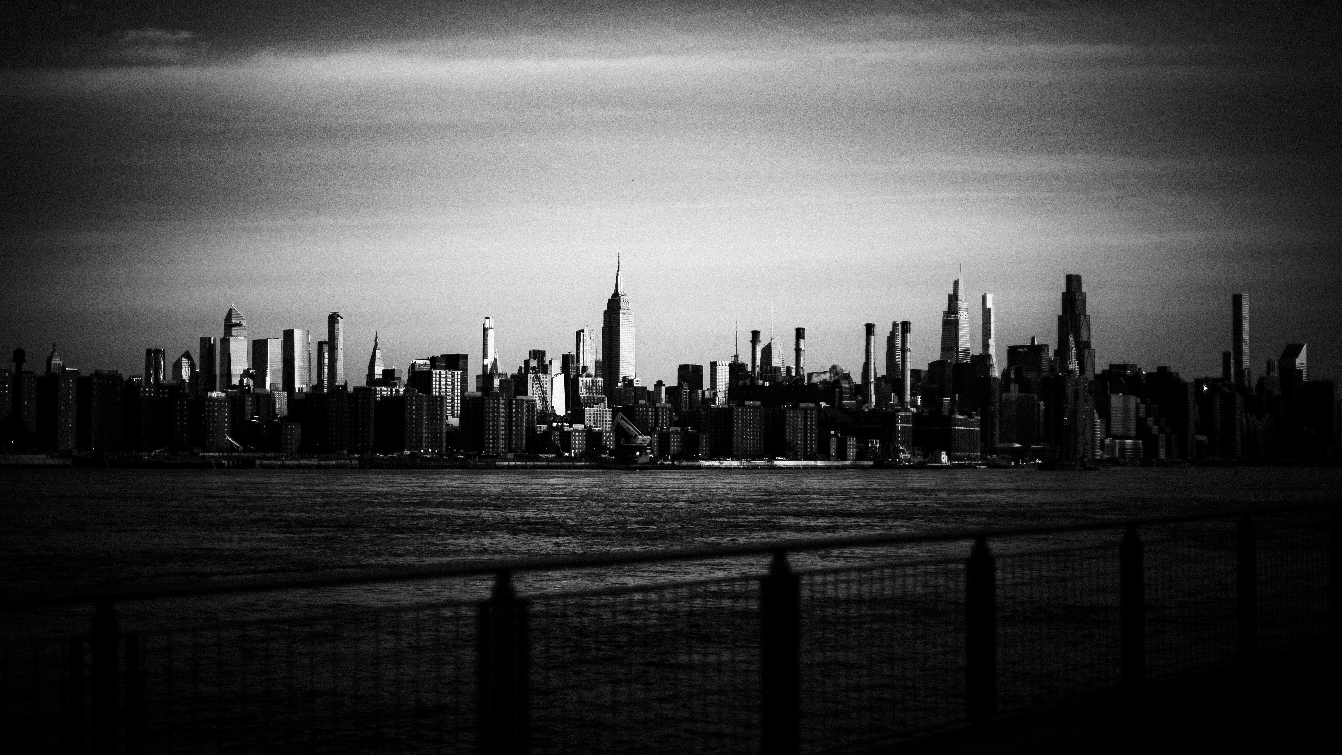 The New York City skyline in black and white across the East River at dusk