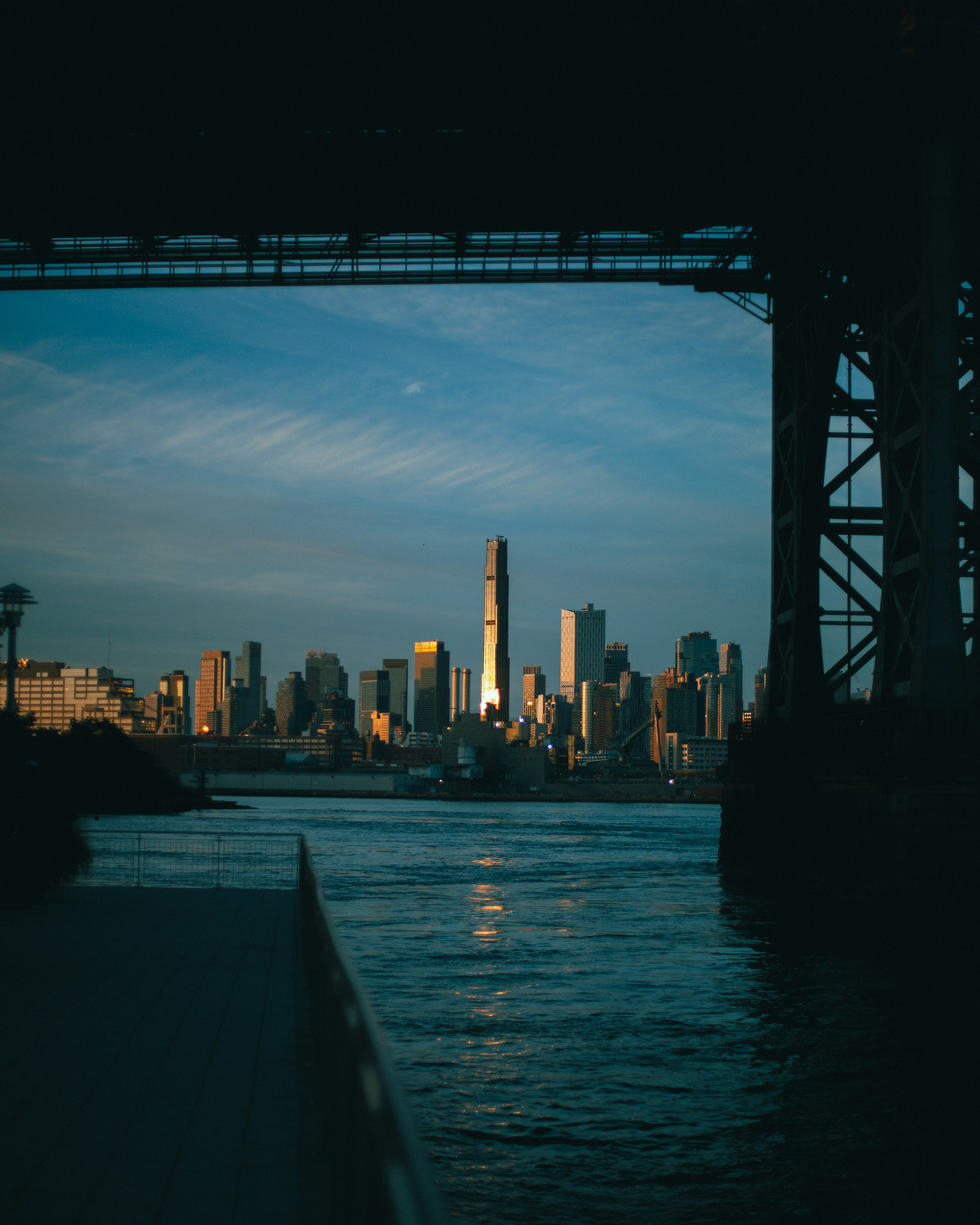 The Manhattan skyline at golden hour viewed from beneath a bridge in New York