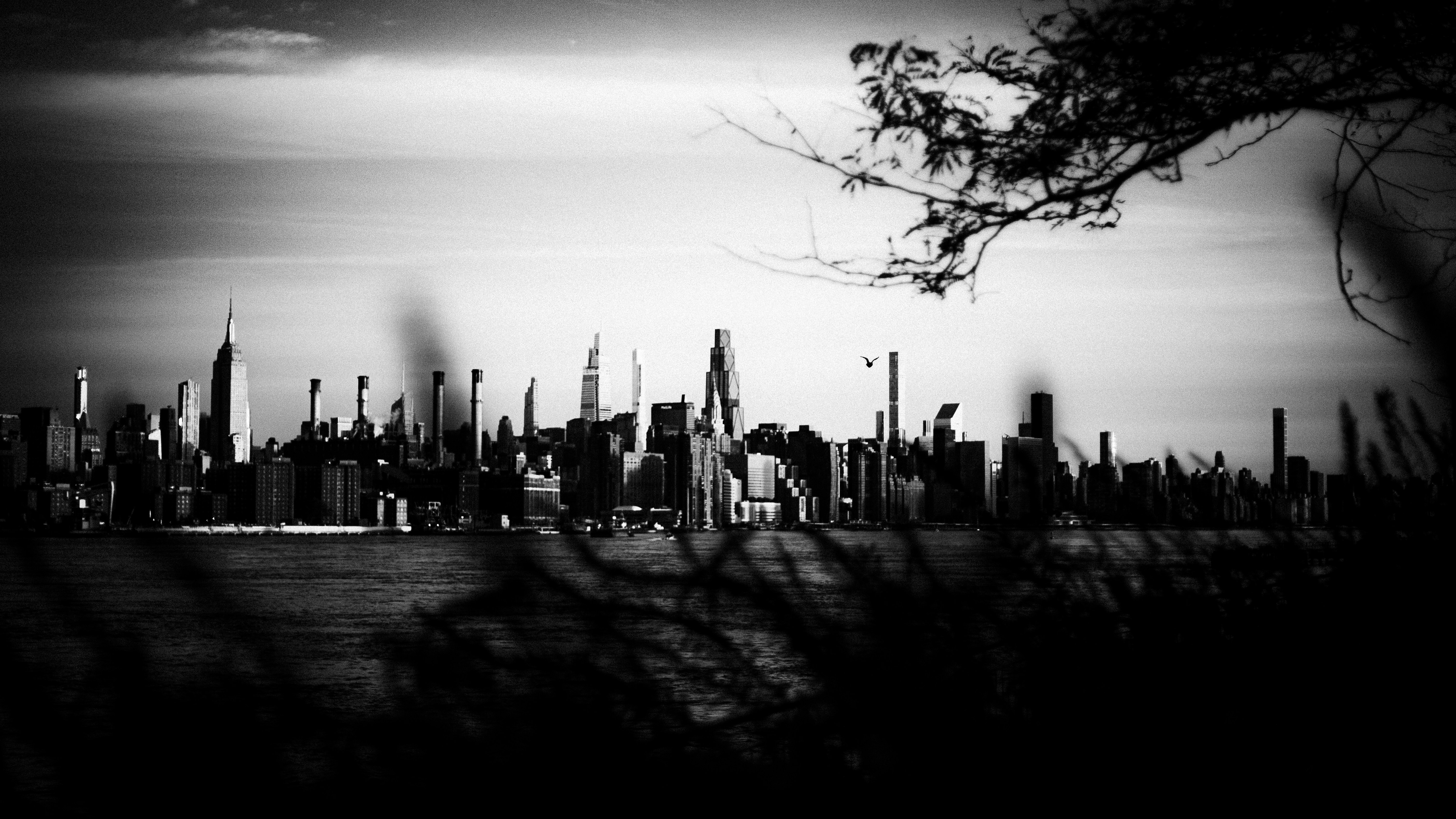 A black and white view of the Manhattan skyline across the water in New York