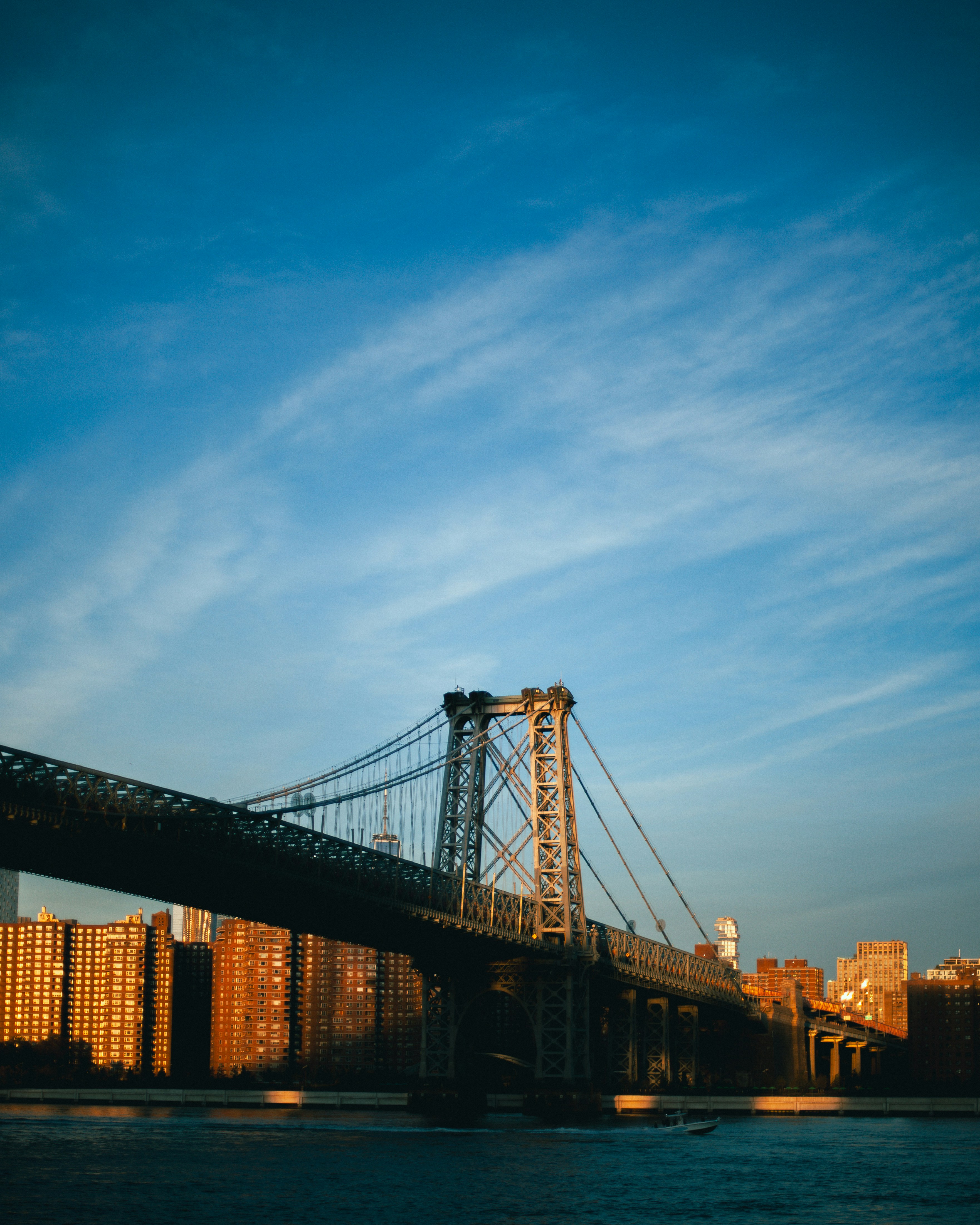 The Williamsburg Bridge spanning the East River with Manhattan buildings in the golden light of day