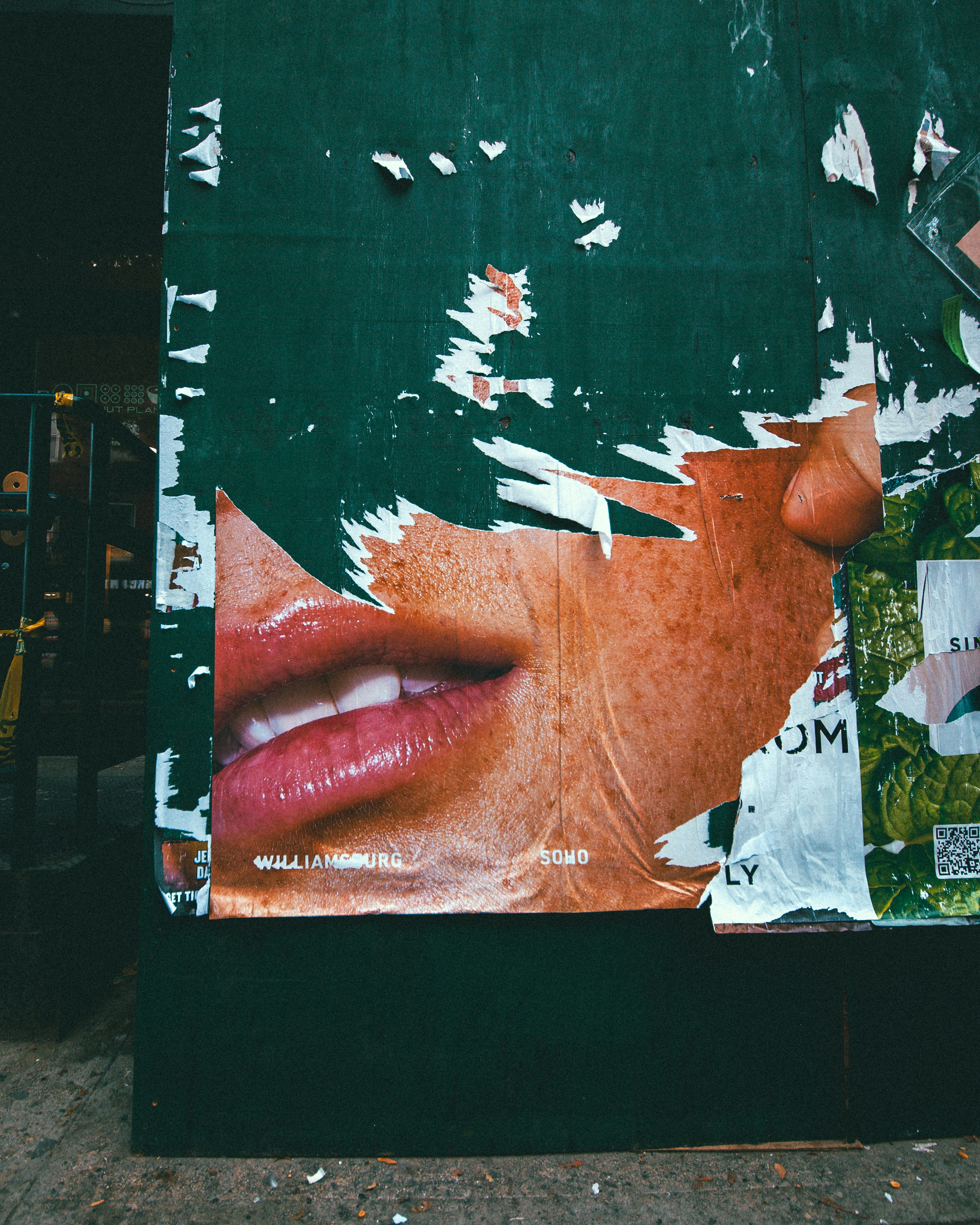 Torn advertising posters on a dark green wall in New York City