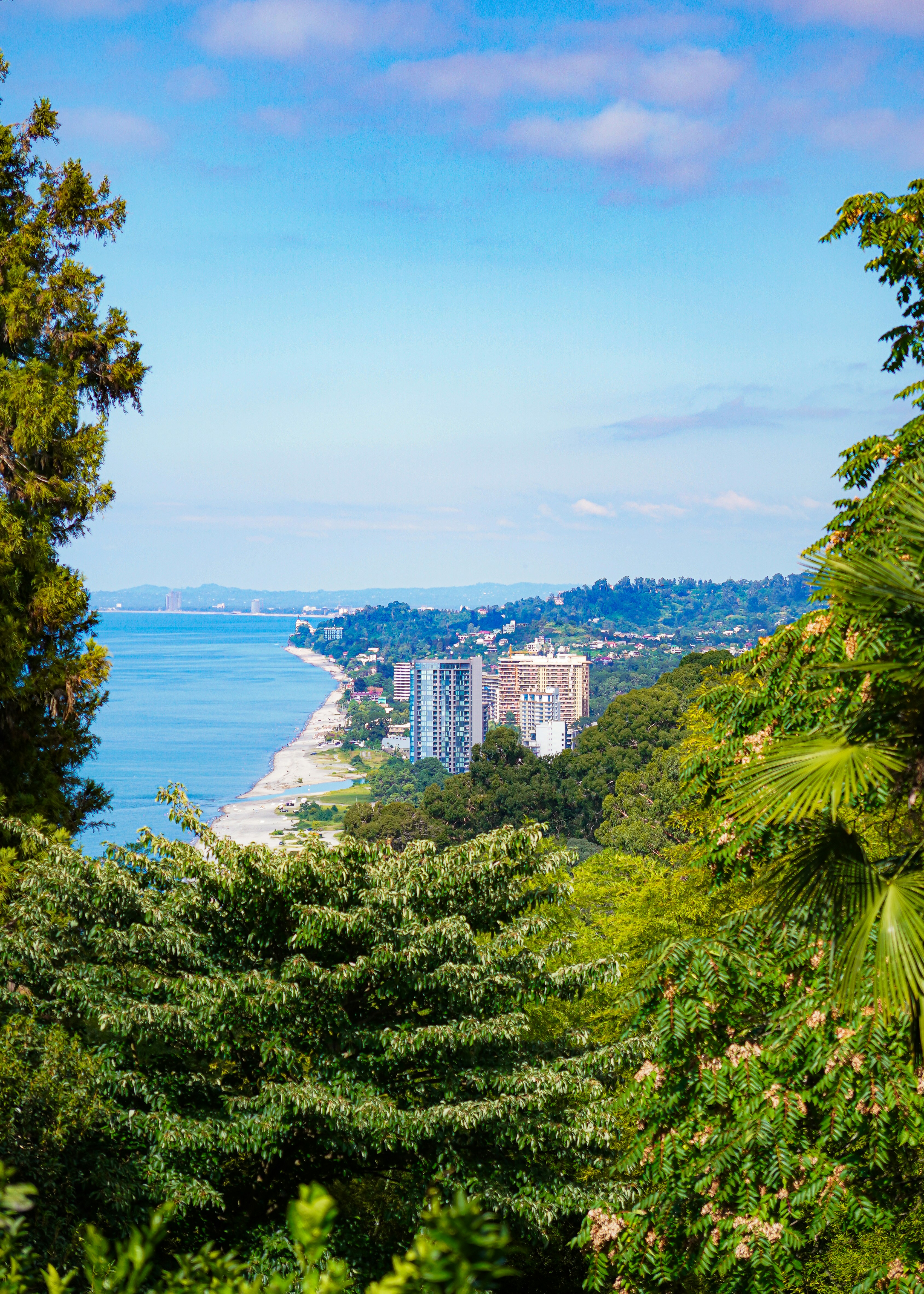 A coastal city with high-rise buildings along a sandy beach under a clear blue sky