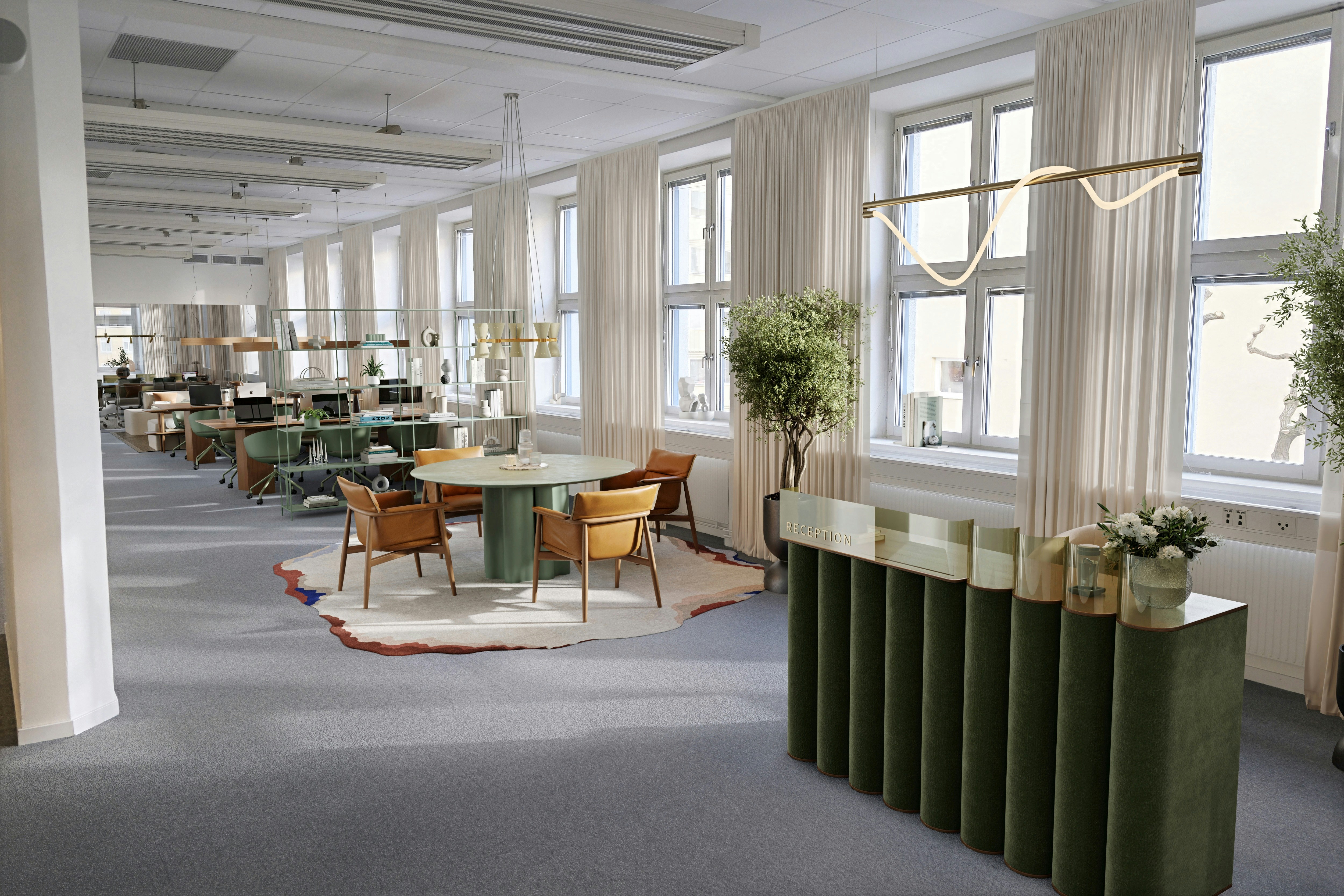 A modern office reception area with a green velvet desk and a round table with leather chairs