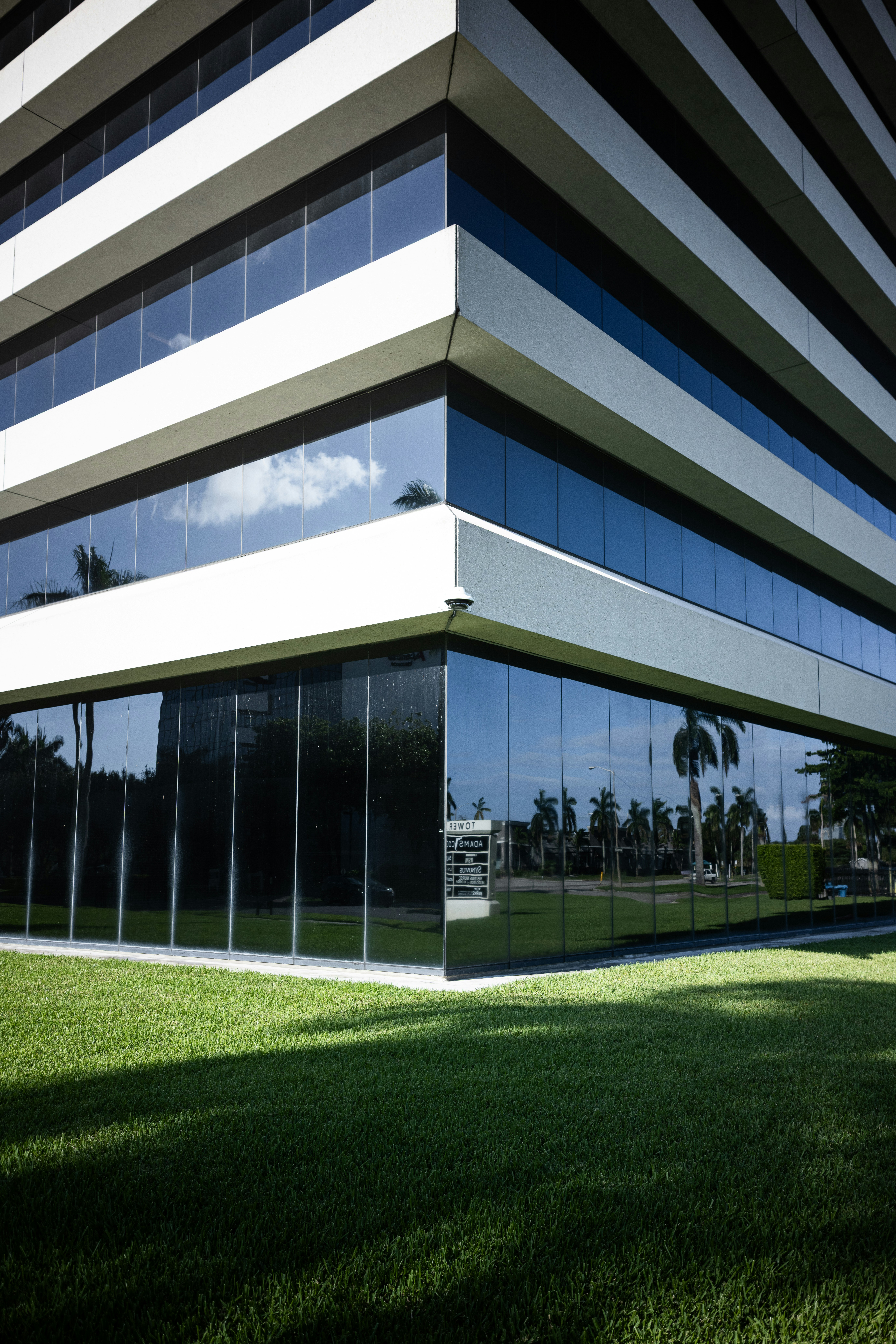 The corner of a modern office building with reflective glass windows and white concrete bands