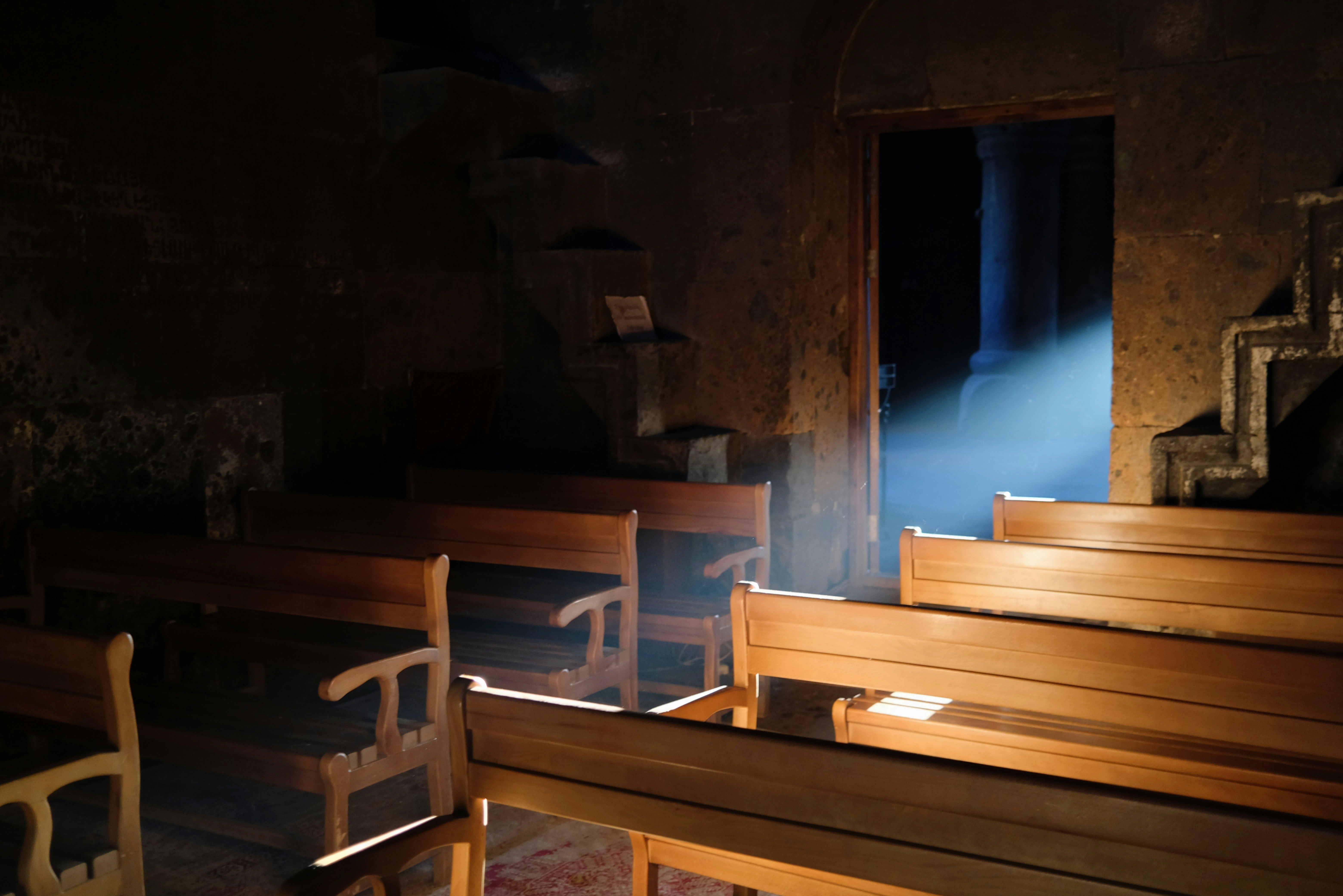Wooden pews in dim stone church - Free Photo on Unsplash