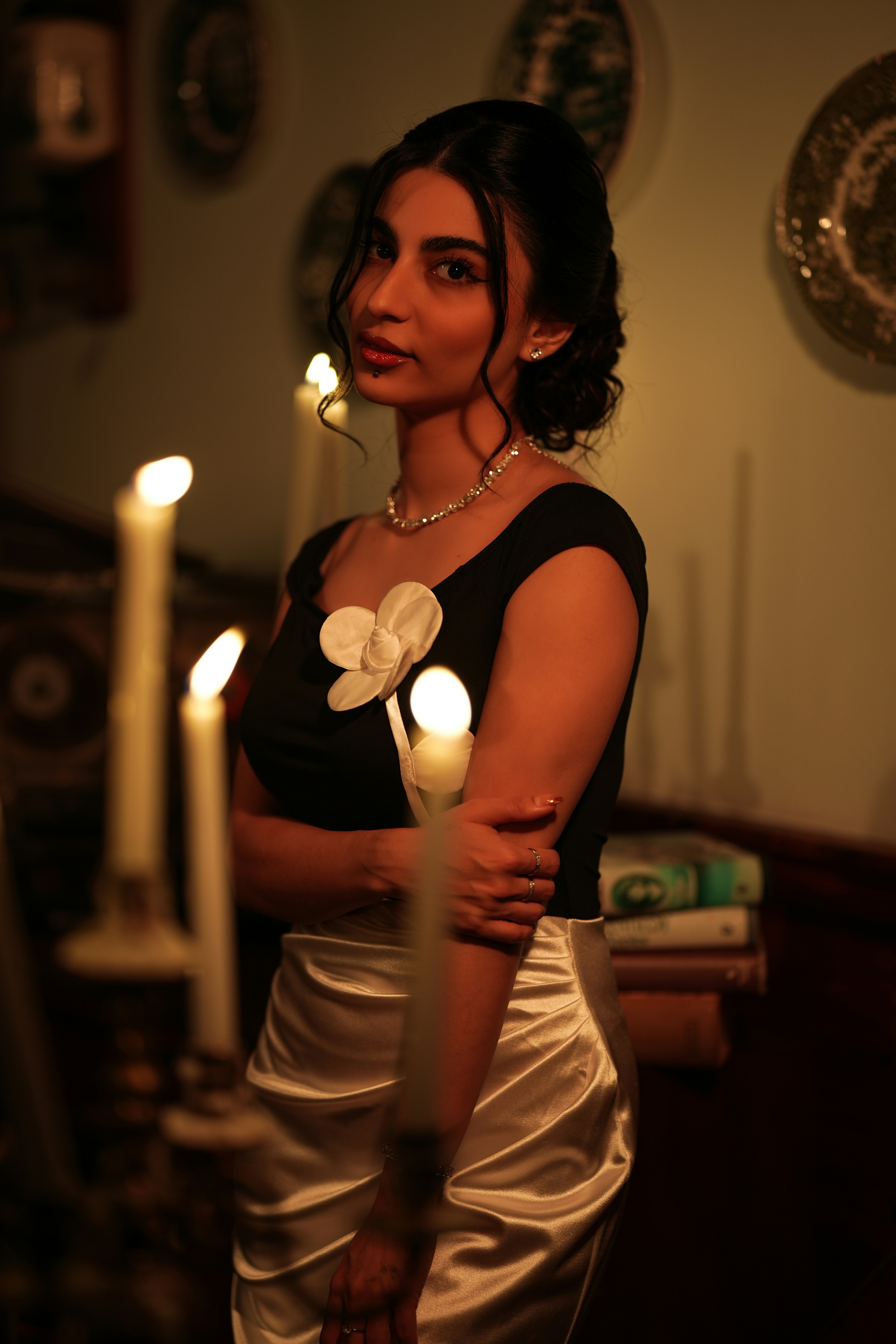 By candlelight in a black top with a white flower and satin skirt