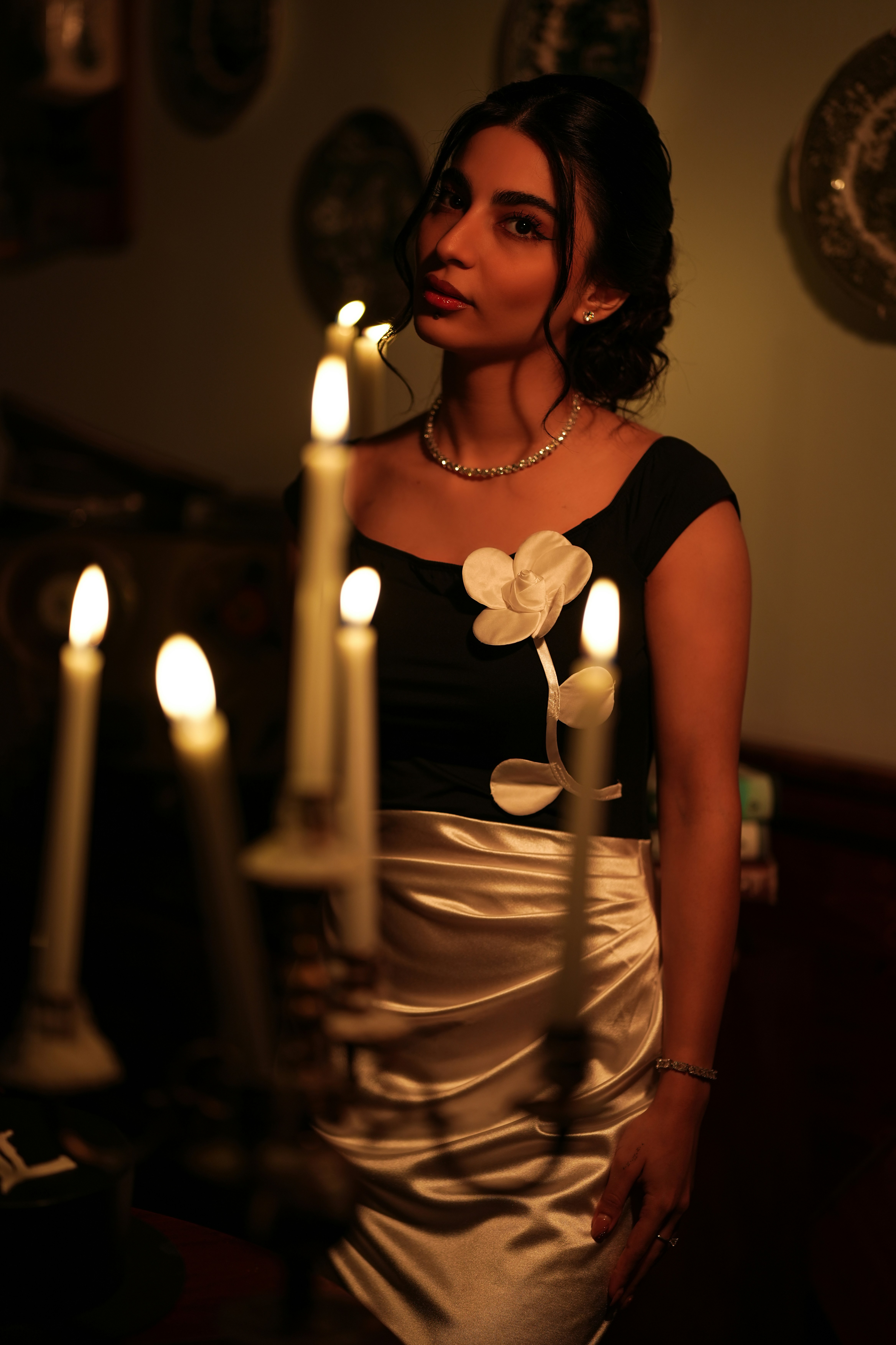 Behind a row of candles in a black top with a white flower