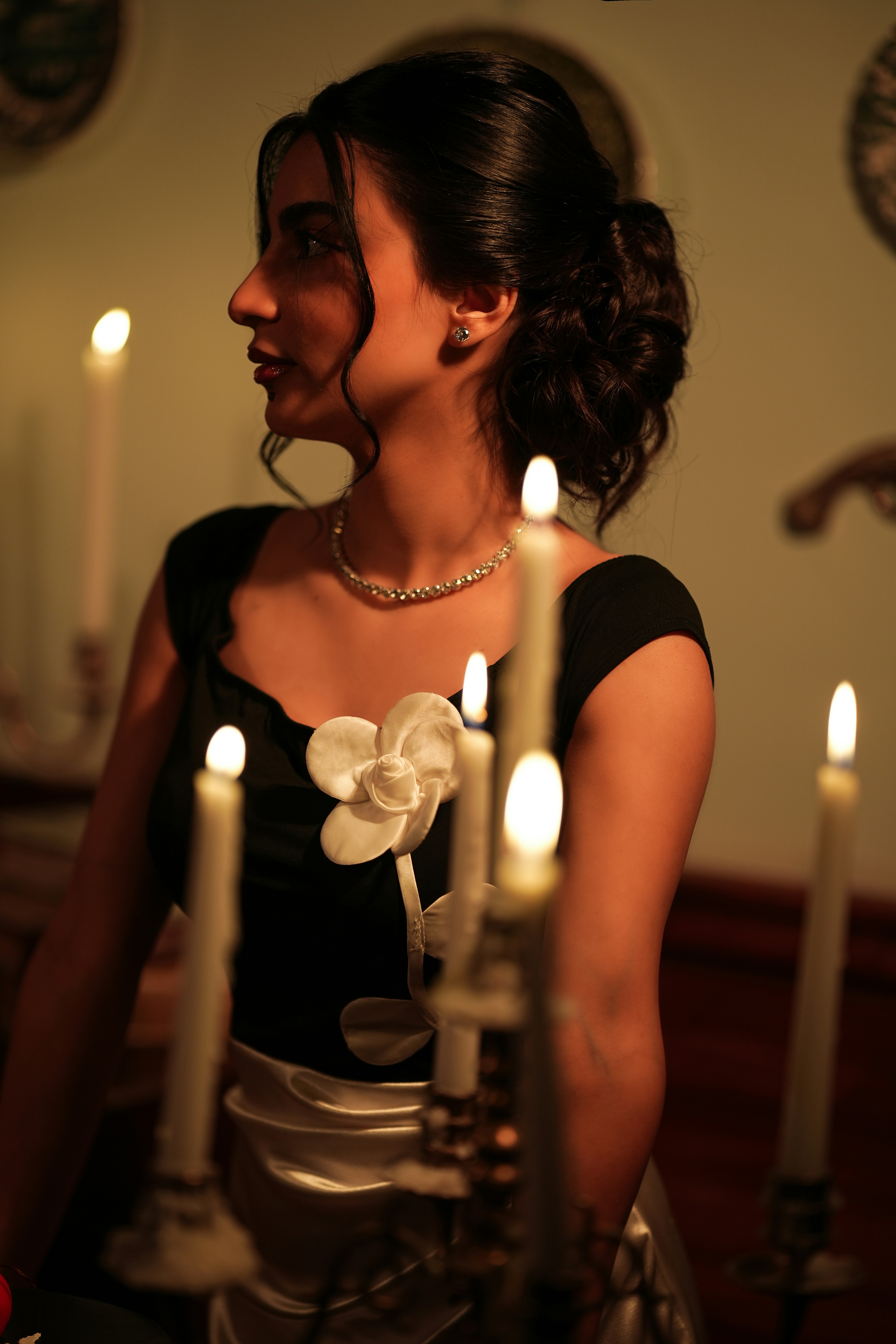 In profile, hair pinned up, candles in the foreground