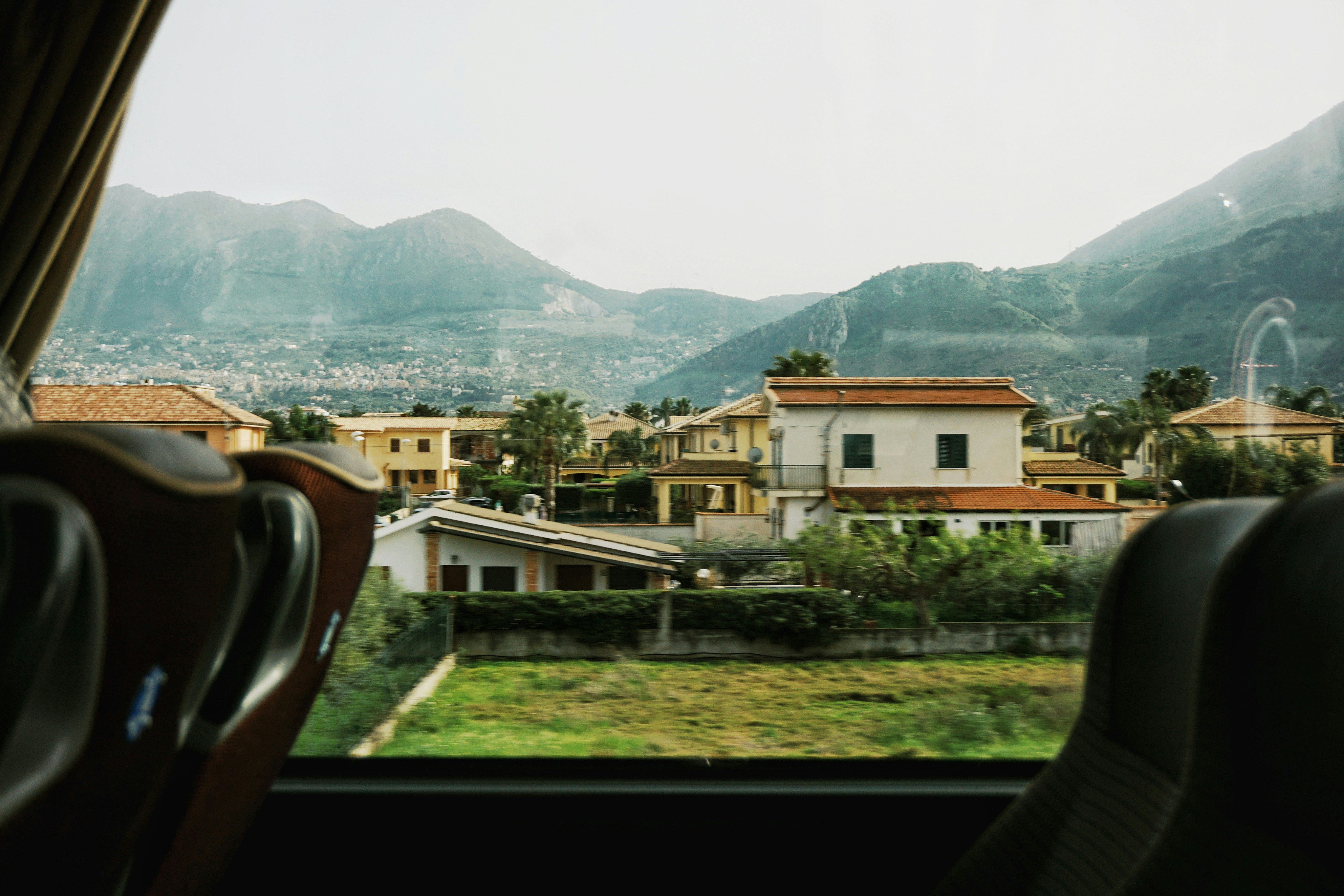 View from a bus window of houses nestled at the base of a mountain range