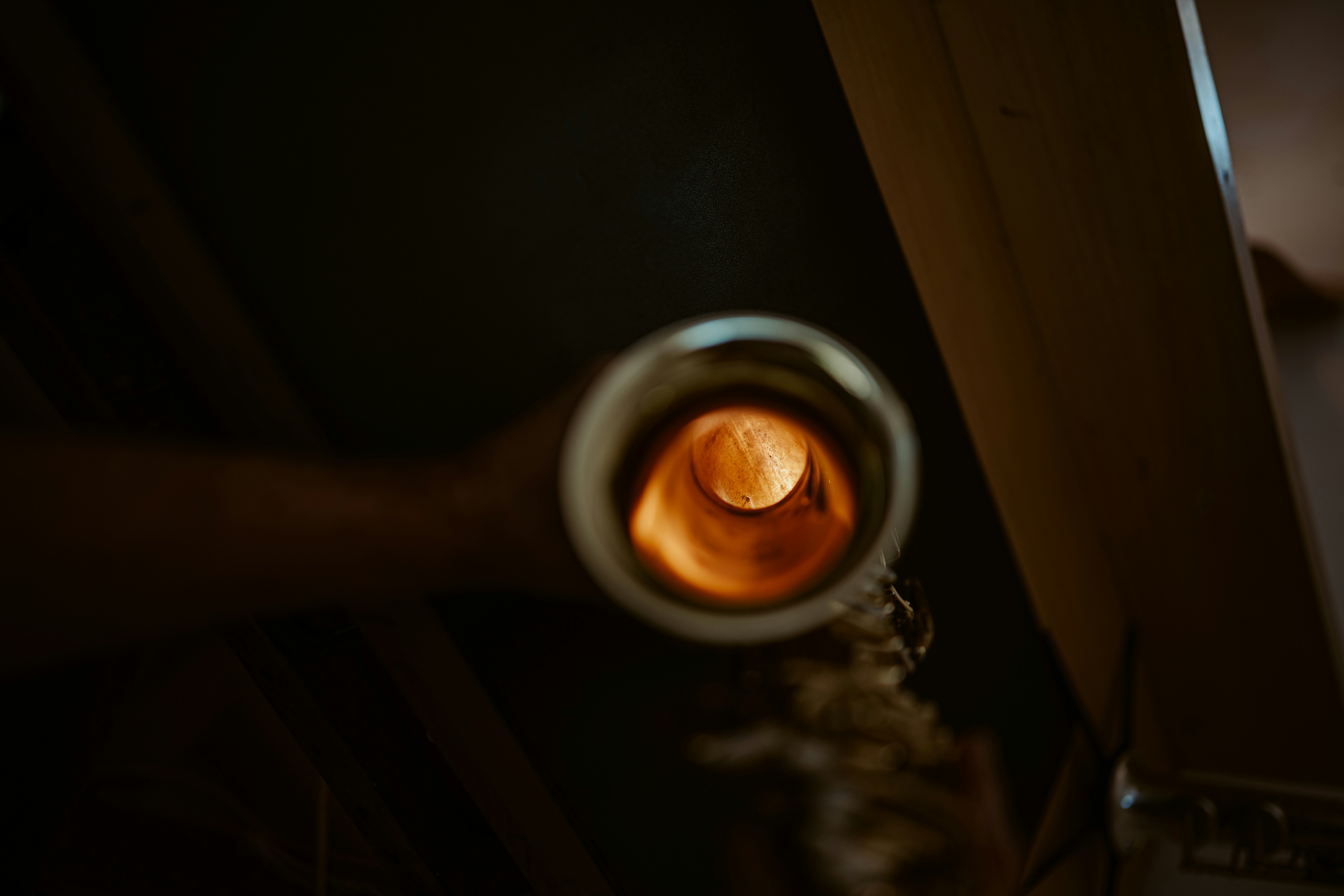 A view looking into the glowing orange interior of a brass saxophone bell