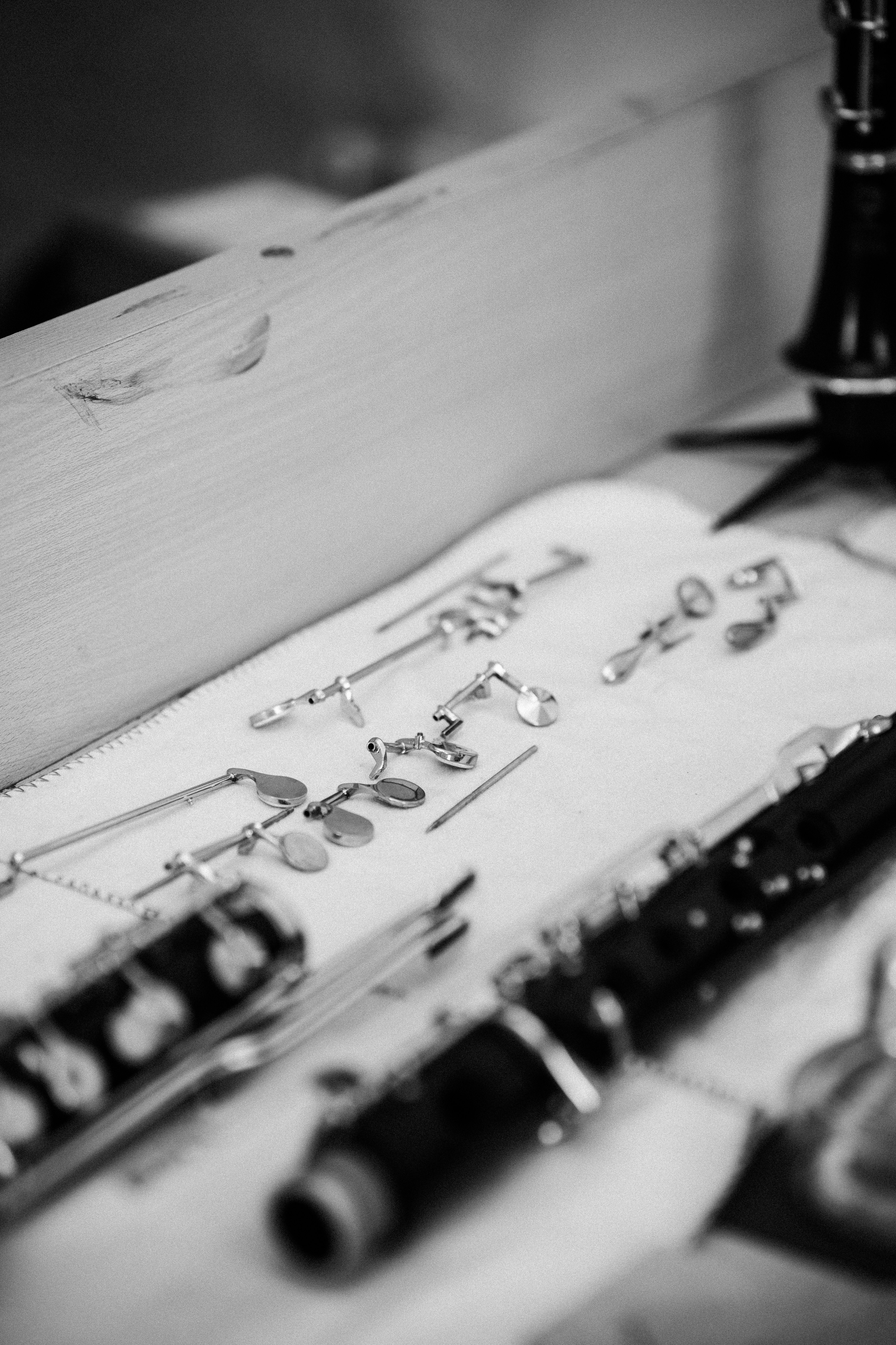 Disassembled clarinet parts laid out on a white cloth for repair in black and white