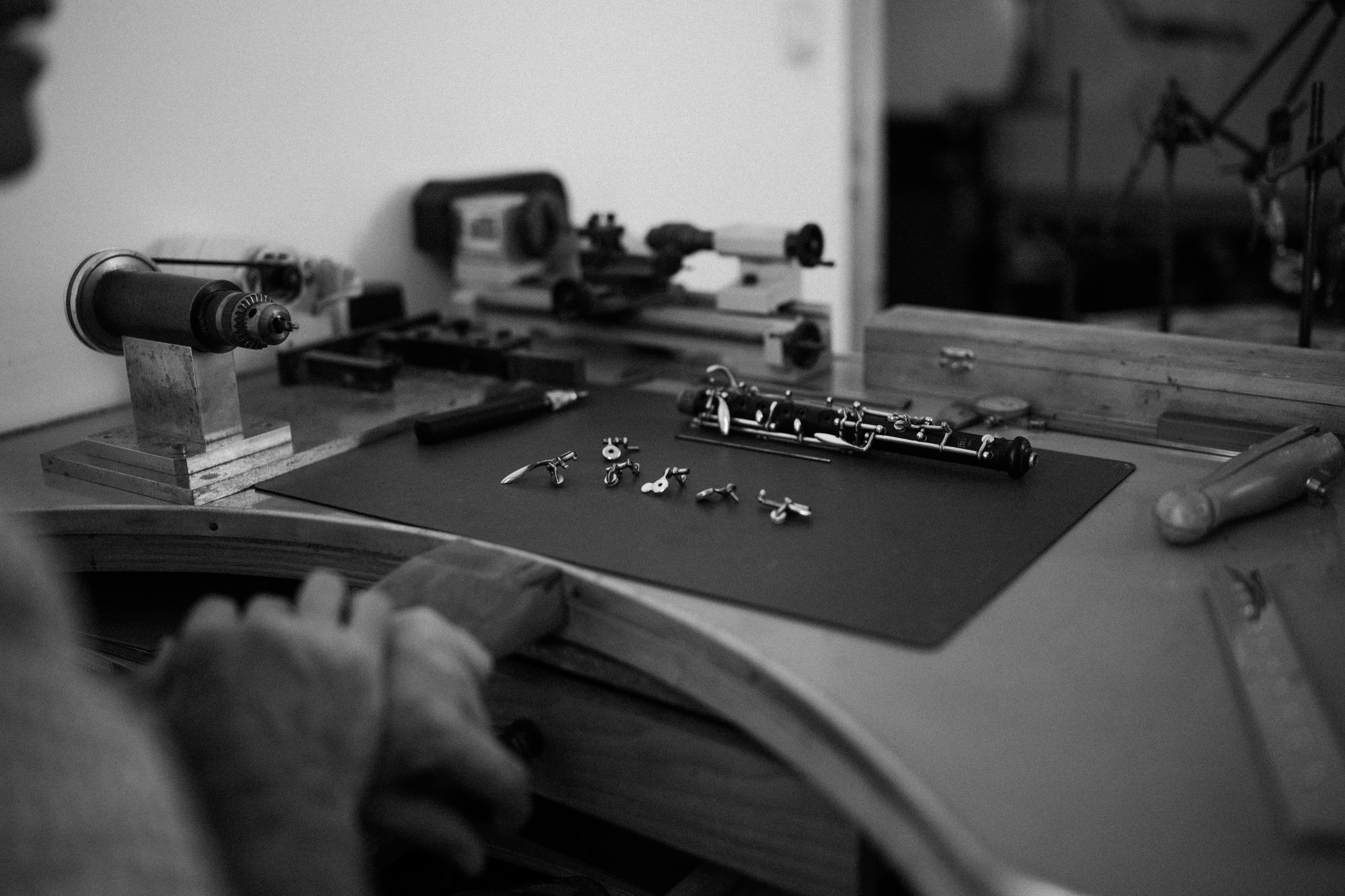 A person working on a disassembled oboe with small metal keys on a workbench