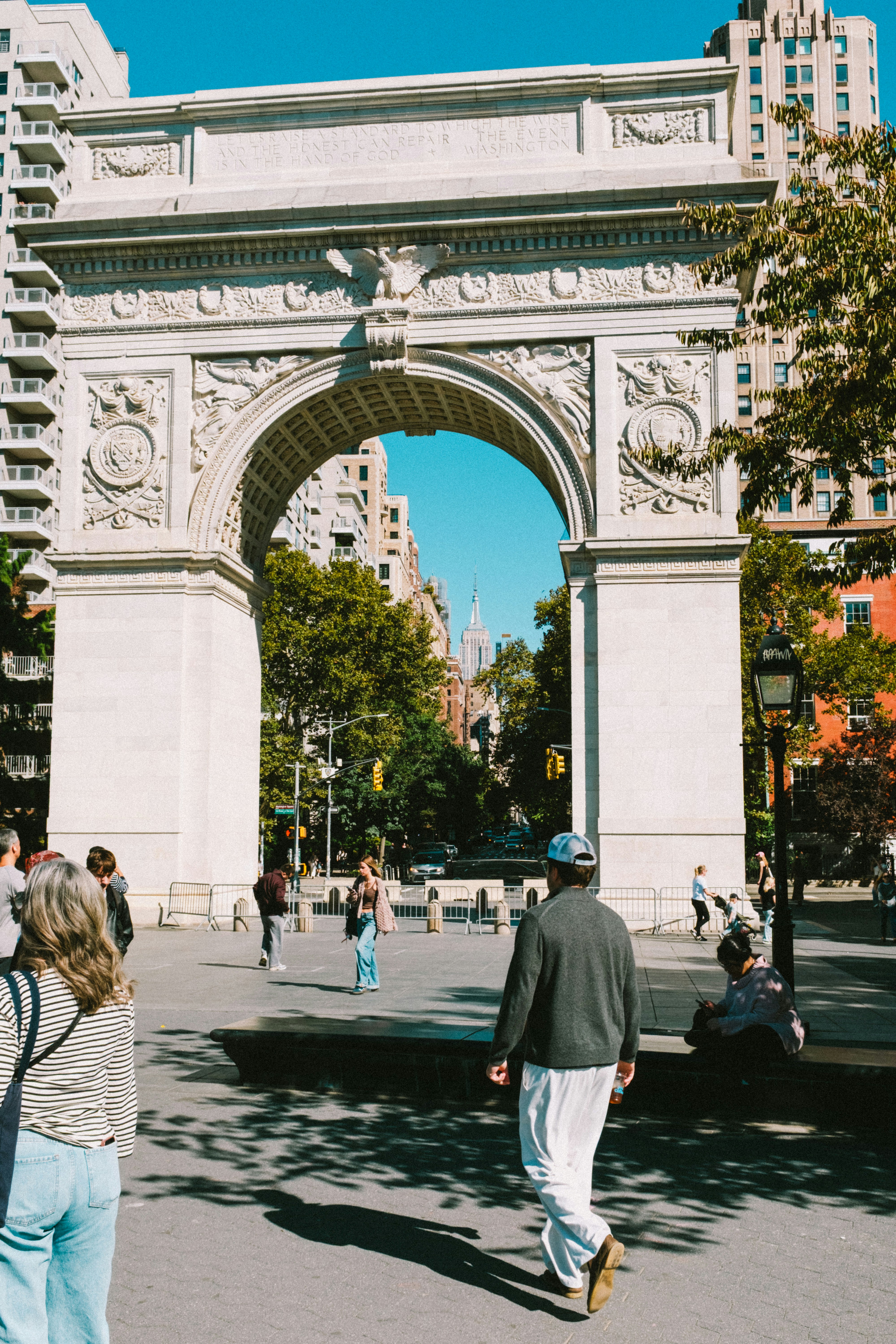 People walking through the Washington Square Arch in New York City with the Empire State Building visible