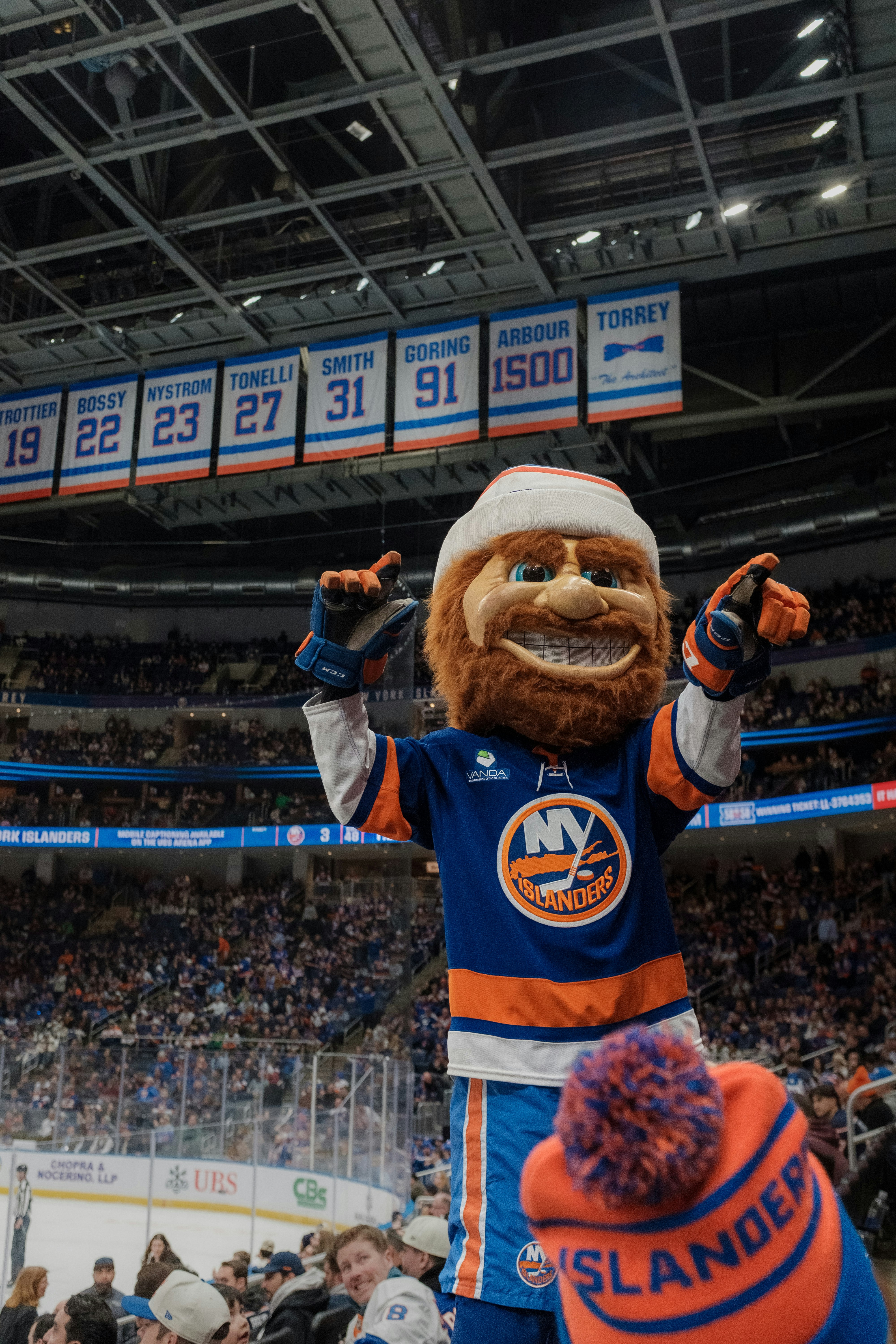 Sparky the Dragon mascot in a New York Islanders jersey at an ice hockey arena