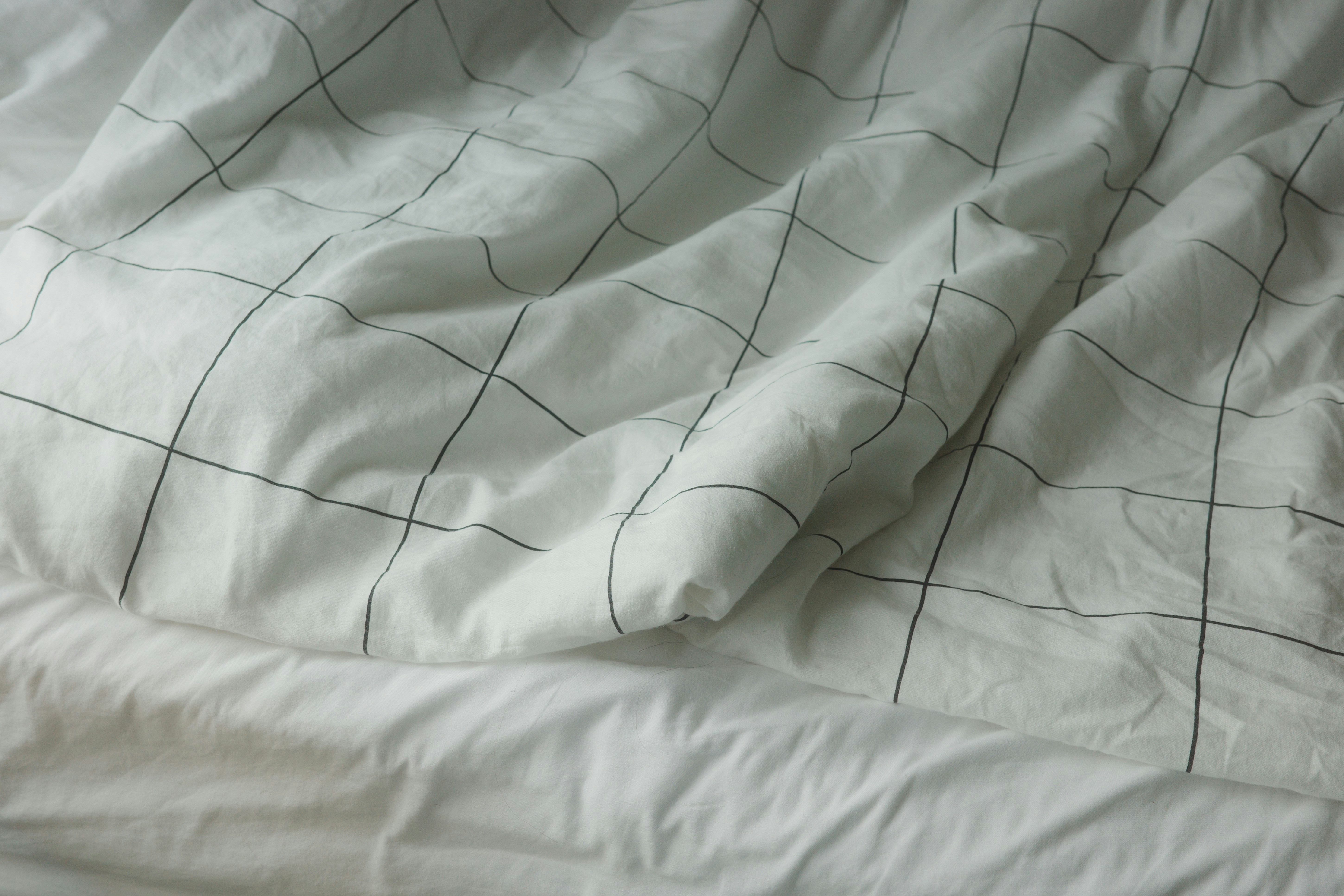 A white bed sheet with a black grid pattern in soft natural light