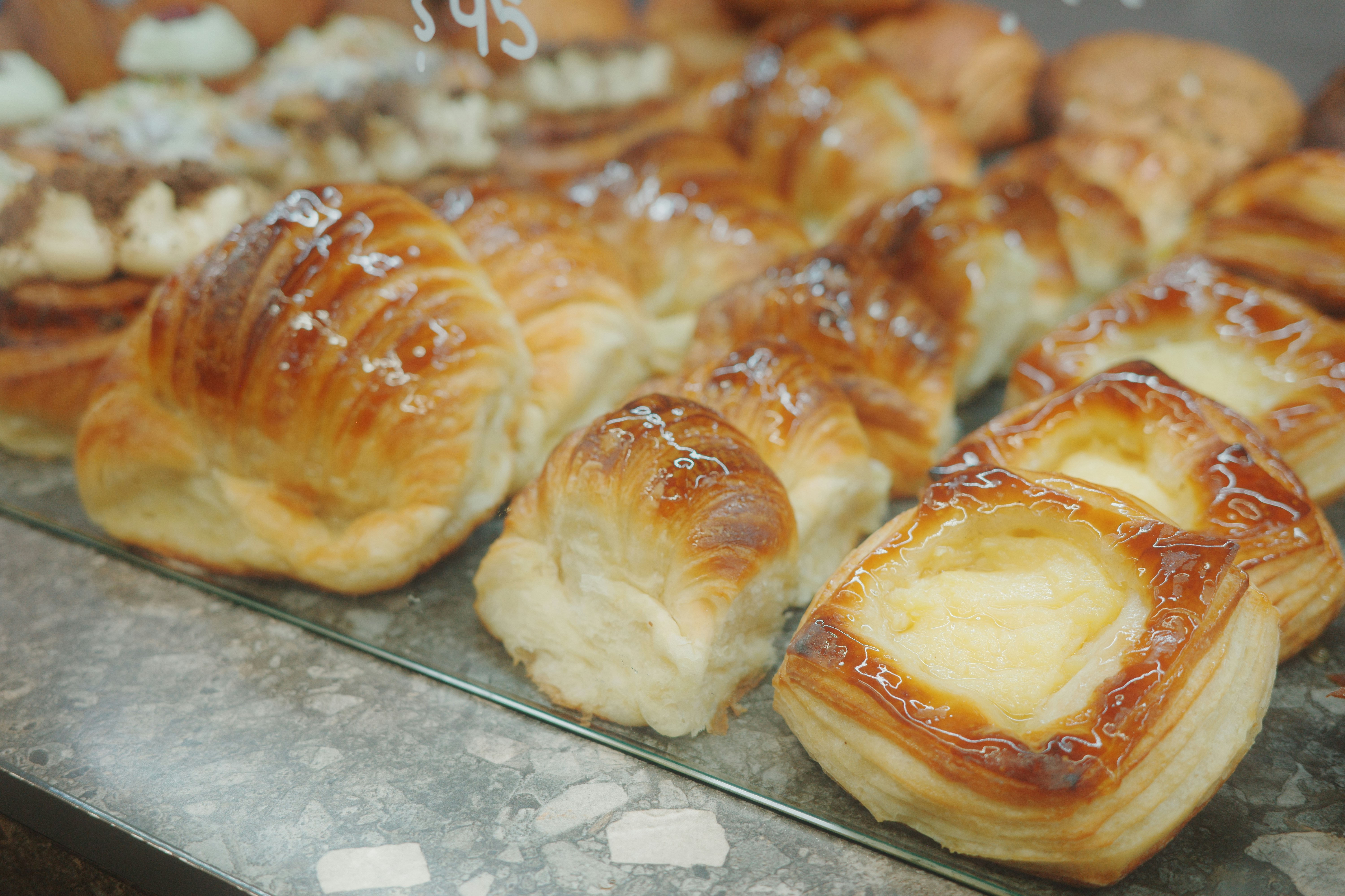 A variety of golden brown croissants and danishes displayed on a grey stone counter