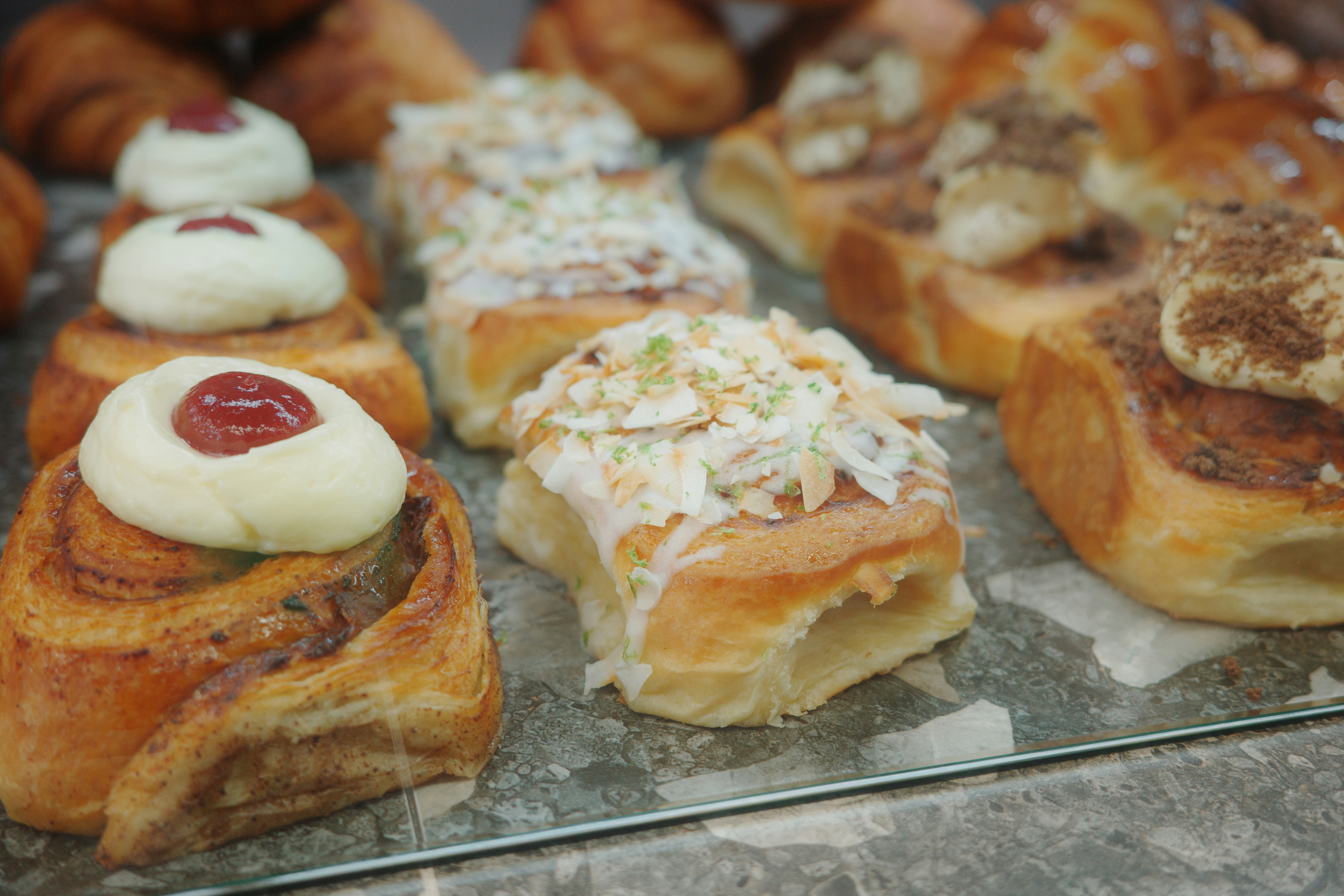 Assorted sweet pastries with cream and toppings displayed on a marble counter