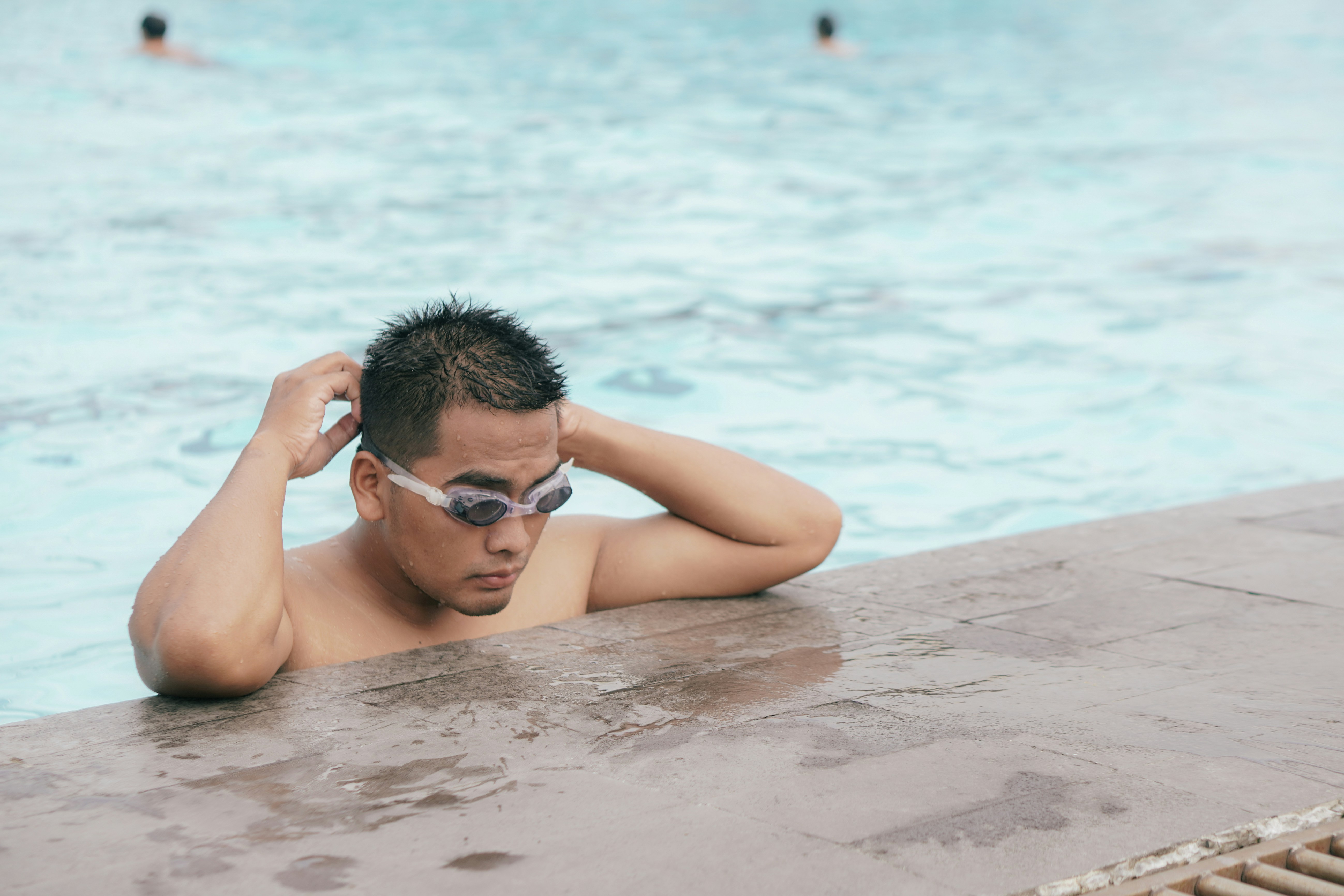 Un nageur ajuste ses lunettes au bord d'un bassin avant l'entraînement (photo d'illustration)
